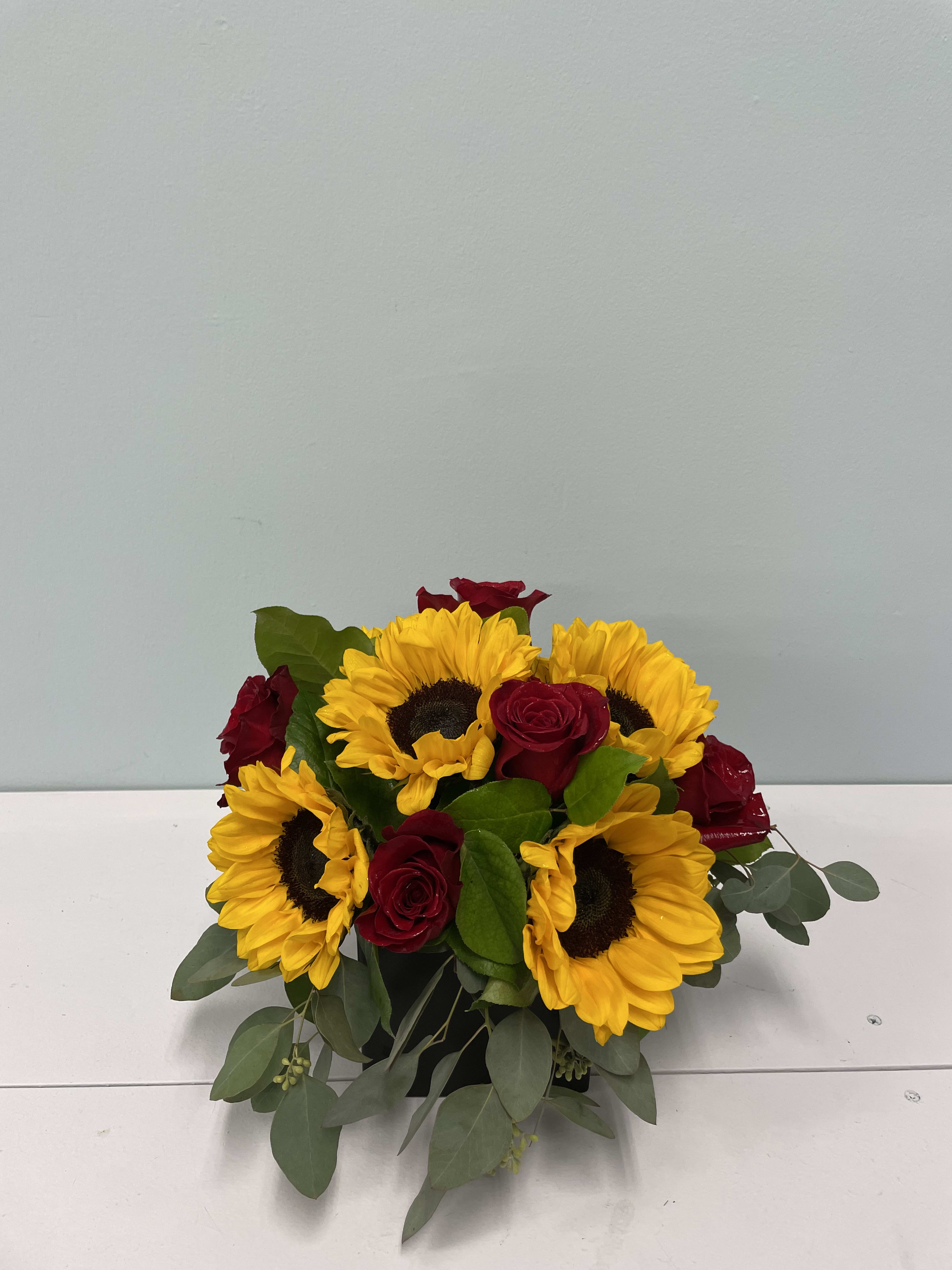 Summer Love Summer Love - A combination of beautiful sunflowers and red roses in a black ceramic vase to give to that special someone. A beautiful arrangement for any occasion.
