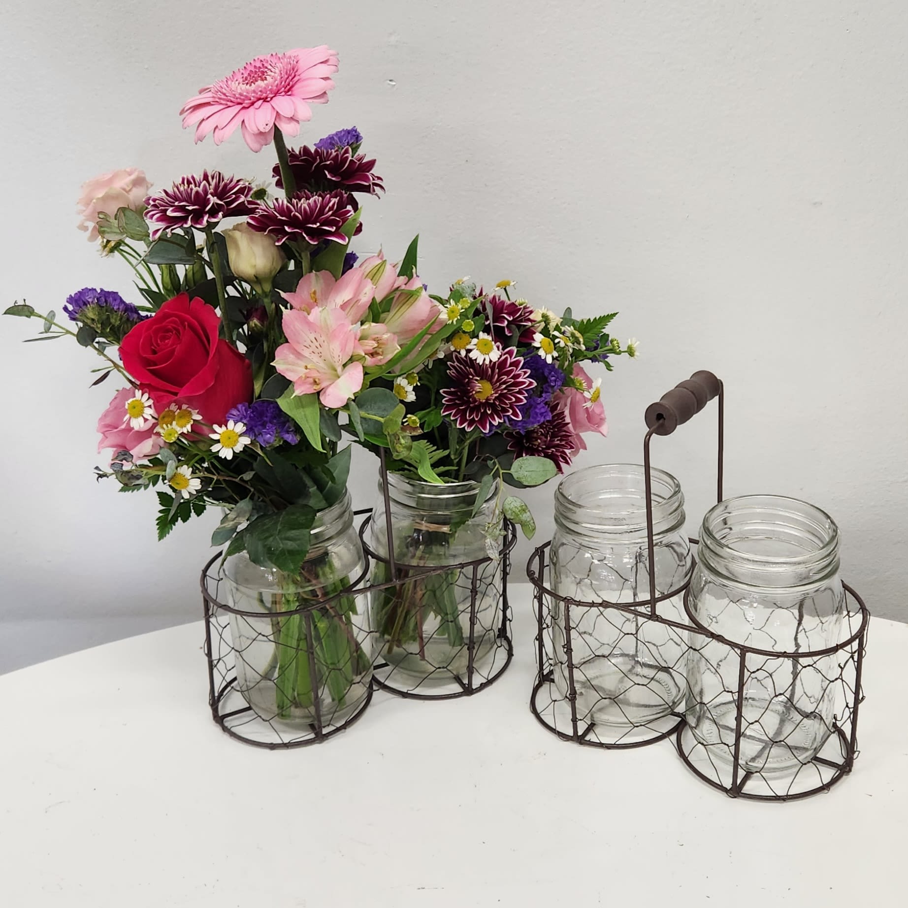 KMD2504 Country Caddy Mom KMD2504 Country Caddy Mom - KMD2504 Country Caddy Mom A charming gift with lasting joy, Little Wire Basket is perfect for the mom who always loves to have a few fresh flowers nearby. This sweet wire basket comes with a handle and two petite glass vases—just the right size for a small seasonal stem or a handpicked garden bloom. We’ve started it off with a cheerful mix of mini germinis, delicate lisianthus, and dainty chamomile for a fresh, meadow-inspired look that feels simple, sweet, and full of love. Whether she fills it later with wild violets and dandelions from the yard, or a few florist favorites, it’s a thoughtful gift that keeps on giving. A delightful surprise for the mom who finds beauty in the little things.