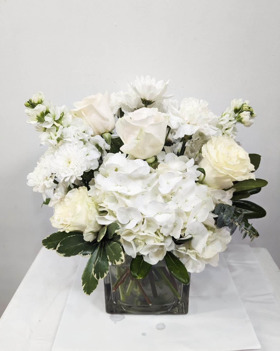 Simplicity  - Simplicity is the perfect gift to wish a happy birthday, show gratitude, or wish a speedy recovery.  Arrangement Details: Includes white roses, stocks, hydrangea and carnations. APPROXIMATE DIMENSIONS: 10&quot; H X 11&quot; W X 11&quot;L