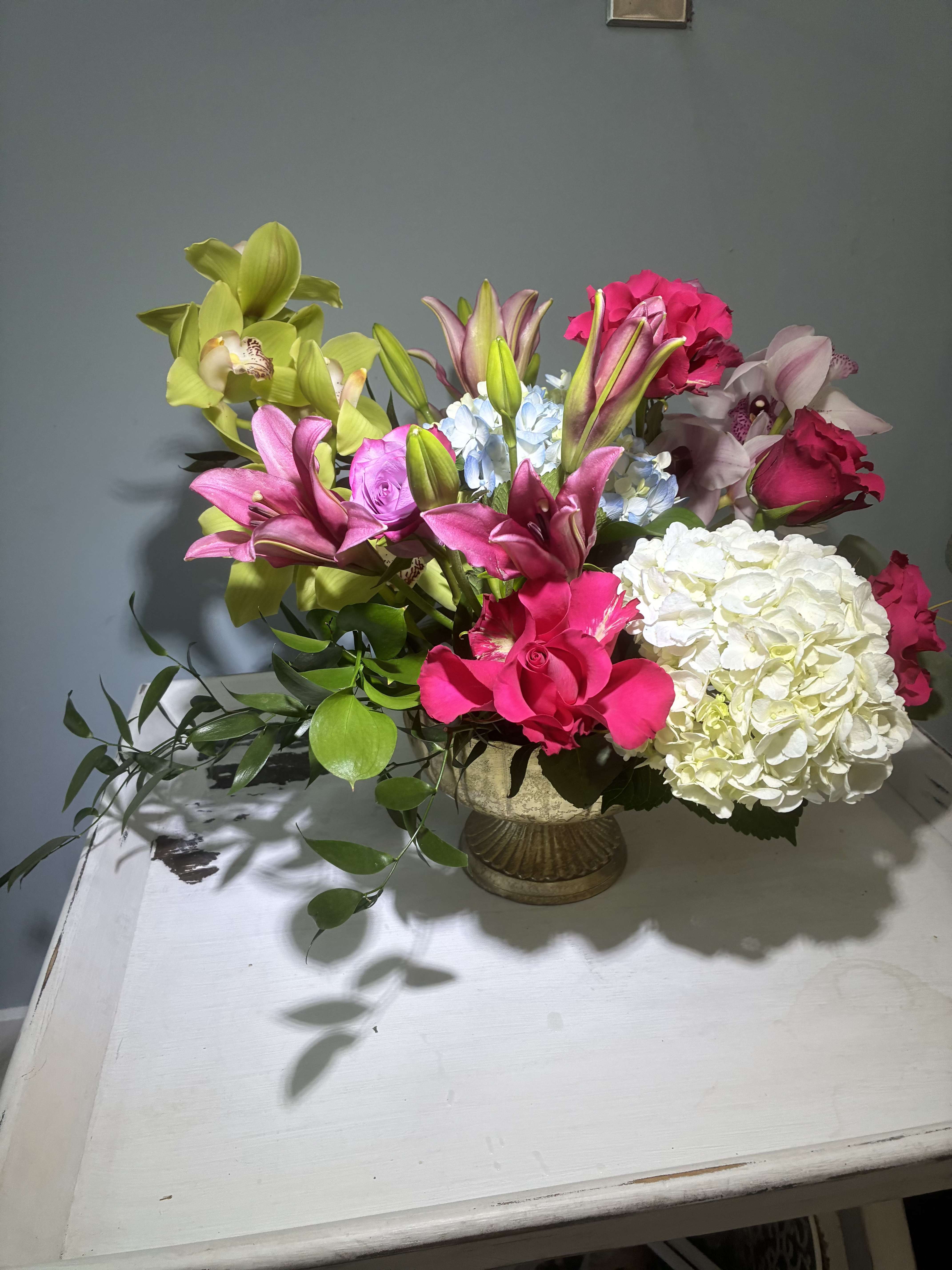 Royalty - a stunning compote gold vase with 2 stems of cymbidium orchs with lillies roses and greens to flow