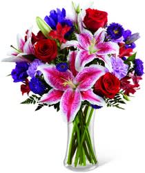 Stunning Beauty Bouquet - The Stunning Beauty Bouquet is an absolutely lovely way to send your love and affection across the miles. This one-sided design features fragrant Stargazer lilies stretch their star-like petals across a bed of rich red roses, lavender carnations, red Peruvian lilies, purple double lisianthus, purple matsumoto asters and lush greens. Presented in a classic clear glass vase, this elegant bouquet is an incredible way to convey your sweetest sentiments.
