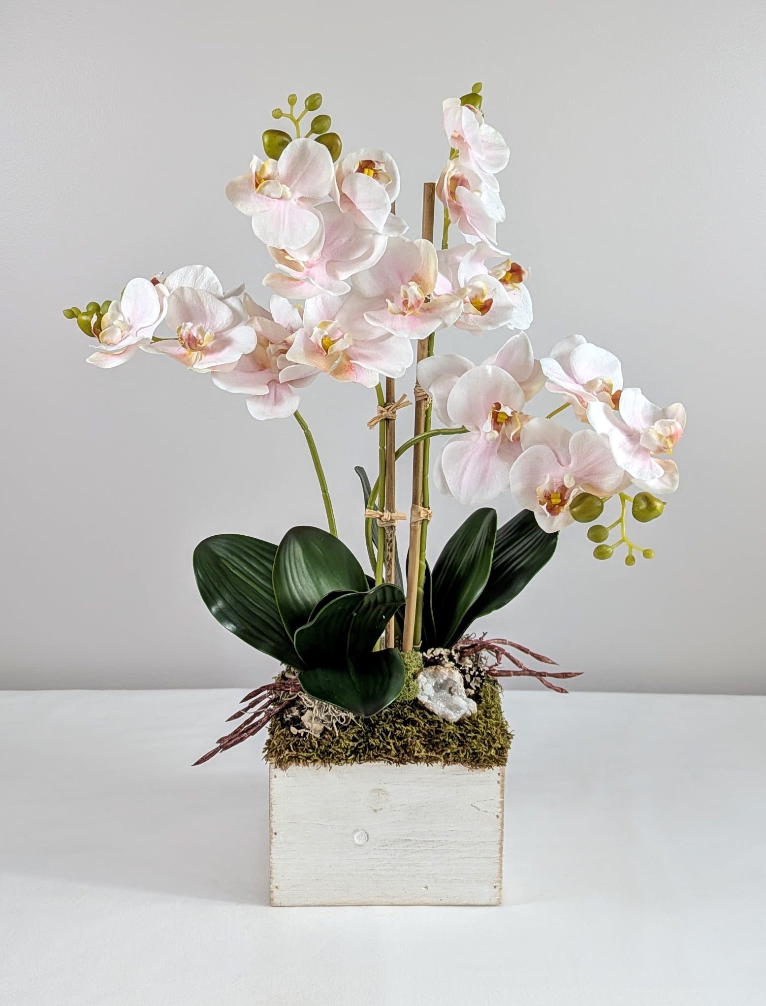 Silk Phalaenopsis Orchid Dish Garden w/Quartz Geode - Light Pink - This one of a kind artificial orchid planter is the perfect gift to give friends and loved ones for any occasion. They are beautiful, everlasting and are a great alternative to traditional flowers. This gorgeous, handcrafted design includes light pink realistic faux blooming orchids accented with a sparkling quartz crystal geode. Other natural elements like, preserved varieties of moss &amp; lichen, also add to the arrangements overall design composition &amp; beauty. This dish garden is designed in a rustic white washed wooden planter adding a touch of charm to the overall feel &amp; look of the piece. This handcrafted gift was made with meticulous attention to detail using high quality items. A stylish orchid planter will add a touch of timeless elegance &amp; sophistication to any indoor space, whether home or office, it will be enjoyed for many years to come!   Measures 21&quot; tall and 17&quot; wide 
