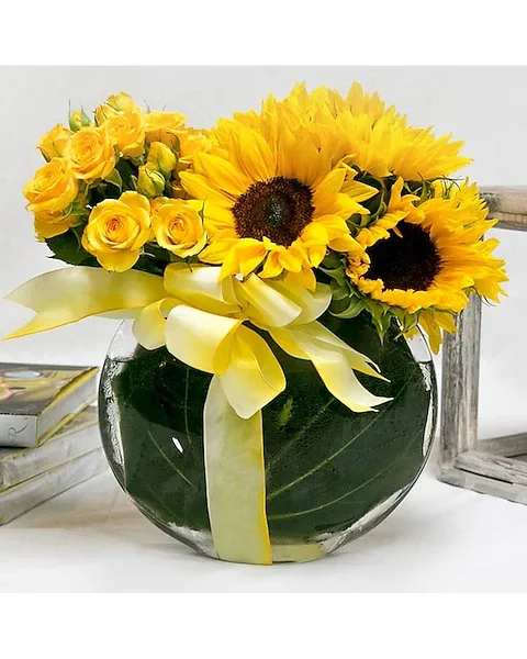 San Diego Sunshine - This mix of yellow spray roses and sunflowers is arranged in a glass vase and lined with ti-leaves and tied-up with a yellow bow. Perfect for any occasion when you want to send a little Sunshine.  All prices in USD ($)