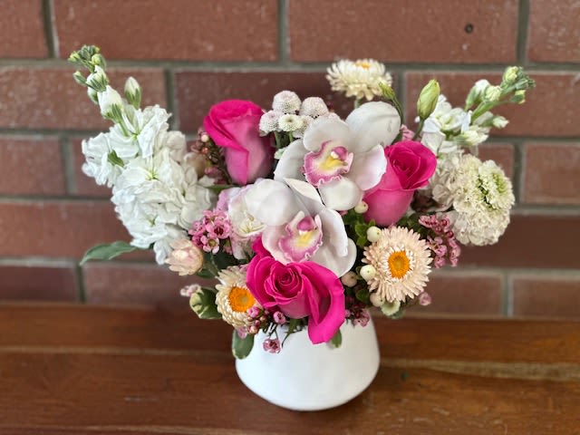 Pink Chic Mini Bouquet - This delightful pink and white mini bouquet, designed by Venetian Flowers, is a charming arrangement that exudes elegance and whimsy. Perfect for expressing love, gratitude, or celebration, this bouquet features a harmonious blend of vibrant and soft hues, creating a visually appealing contrast.  At the center of the bouquet, hot pink roses add a bold pop of color, symbolizing admiration and joy. Their lush, velvety petals create a striking focal point, drawing the eye and conveying a sense of warmth. Surrounding the roses are exquisite white orchids, which bring an air of sophistication and grace. Their delicate and intricate blooms symbolize beauty and strength, enhancing the bouquet's overall appeal.  Complementing these are fluffy white stock flowers, contributing a sweet fragrance and soft texture, while the charming white strawflowers add a touch of rustic elegance, providing a unique contrast with their papery petals. Delicate lisianthus, with its ruffled blooms, adds softness and depth, rounding out the bouquet with a graceful flourish.