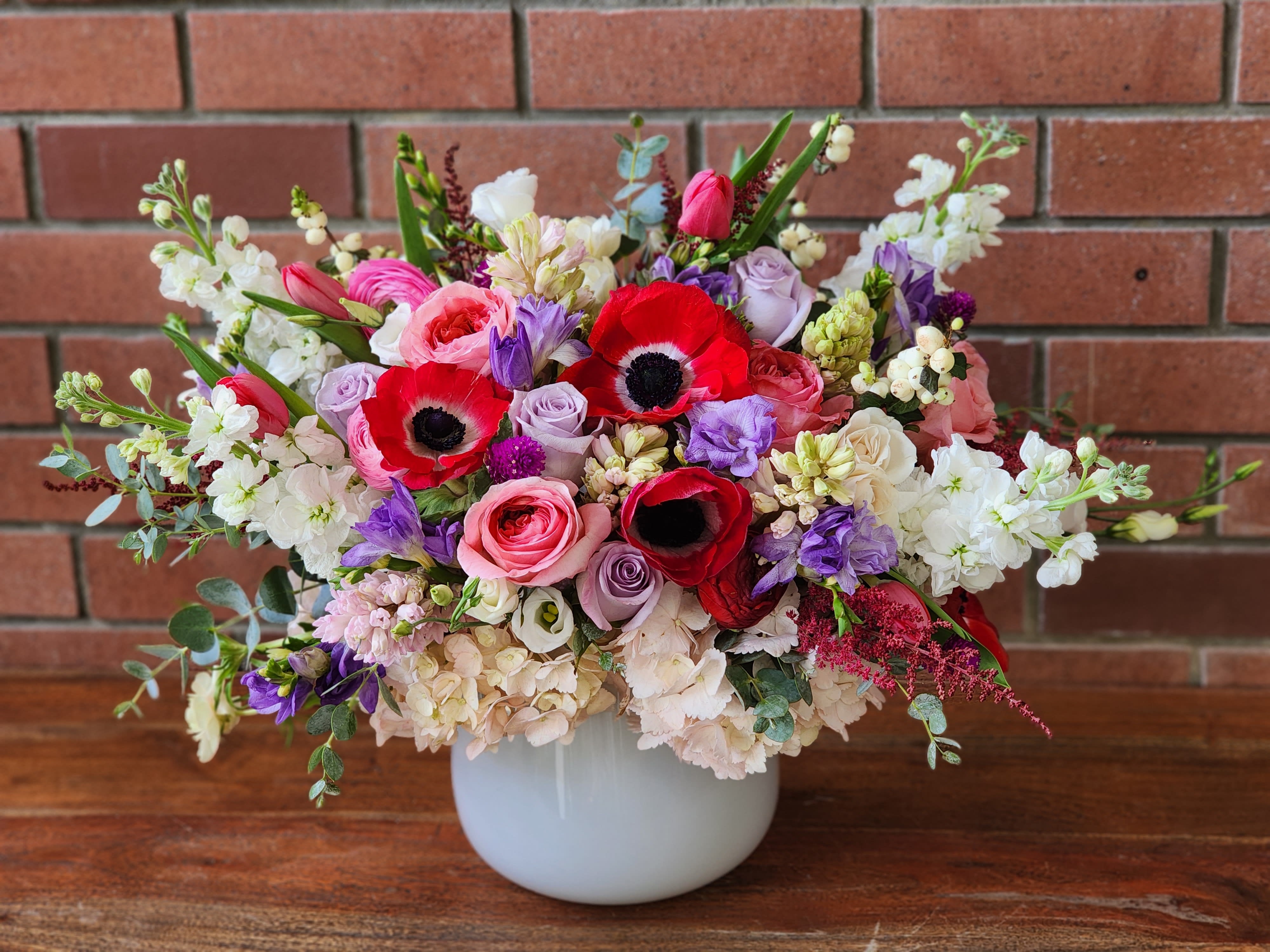 Sweetest Devotion Sweetest Devotion - Fluffy hydrangeas, fragrant stock. Anemones, lavender roses, pink roses, tulips, freesia all together a stunning arrangement in a beautiful heavy glass white vase.