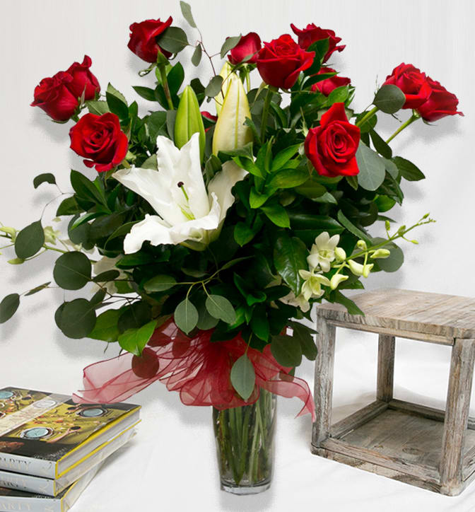 Signature Rose Arrangement RAS - 1 dozen roses: $125 2 dozen roses: $210 3 dozen roses: $325   If reserving outside of dates above, please call the store for lower pricing.   A stunning mix of our premium long-stem roses, casablanca lilies and dendrobium orchids beautifully arranged in a clear glass vase and accented with flowing french ribbon. Chose from red, pink, yellow, white or peach roses.