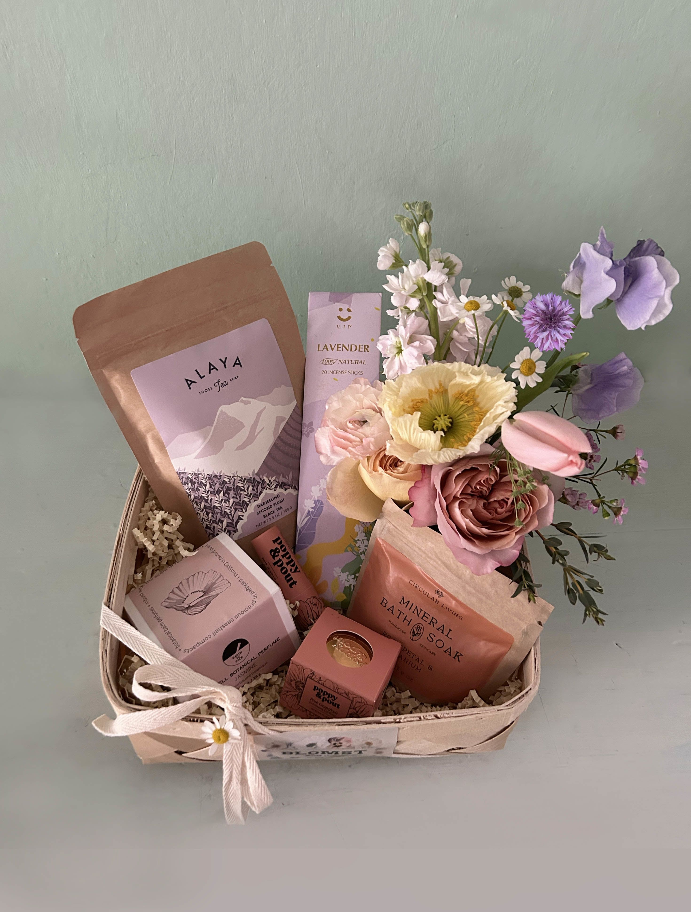 Hailey Healing Box - Lots of heavenly healing goodness in beautiful desert colors in this sweet luxurious care box. Organic and sustainable beauty and wellness products, tea and flowers - to offer a soothing, healing energy for the recipient.  Earth Tu Face pure botanical balm perfume in a real sea shell: Organic cold-pressed safflower, beeswax, and sunflower-derived vitamin E make up the base of this solid perfume. Real Jasmine blossoms, oils of Jasmine.. Circular Living Rose petal and Geranium bath soak: A luxurious mineral soak for sore muscles with rose, geranium, and lemon to balance the skin and cleanse the mind and body. Alaya Darjeelling Tea: Harvested in the second picking of the year, Darjeeling Second Flush tea comes from the unique terroir of this Himalayan region. Certified organic. Organic and regenerative tea, sourced directly from people and planet-friendly Indian farms. Poppy and Pout Pink Grapefruit lip balm: Natural lip balm formula is as smooth as can be. Each cardboard tube is filled from the bottom to the top with lip hydrating goodness. Poppy and Pout Pink Grapefruit lip scrub: Exfoliating Lip Scrub will exfoliate dead skin and leave your lips feeling soft and smooth! LAvender irganic incense sticks in beautiful packaging. Mini Blomst arrangement of fresh, natural stems in a small cylinder vase. All placed in a wooden square box or wooden basket (10 by 10 by 4). Ready for hand delivery in LA. For shippable gift boxes: www.blomstlosangeles.com   
