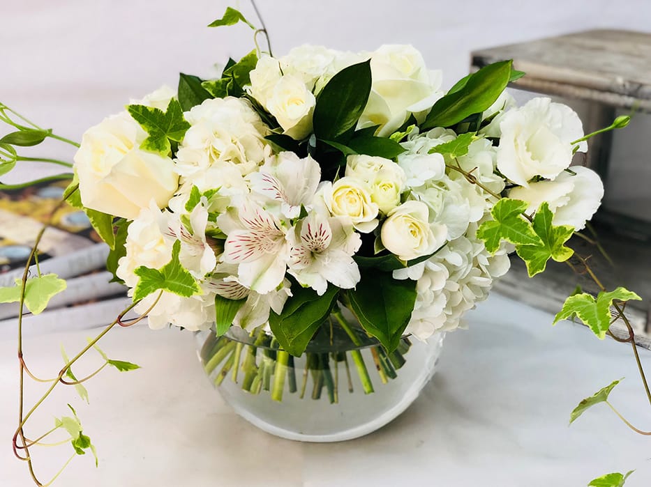 Timeless V12-3 - An amazing green and white mix of Spray Roses, Hydrangea, Stock, other seasonal flowers and Ivy in a clear glass bubble bowl. NOTE: ALSO AVAILABLE IN SPRING COLORS/FLOWERS.