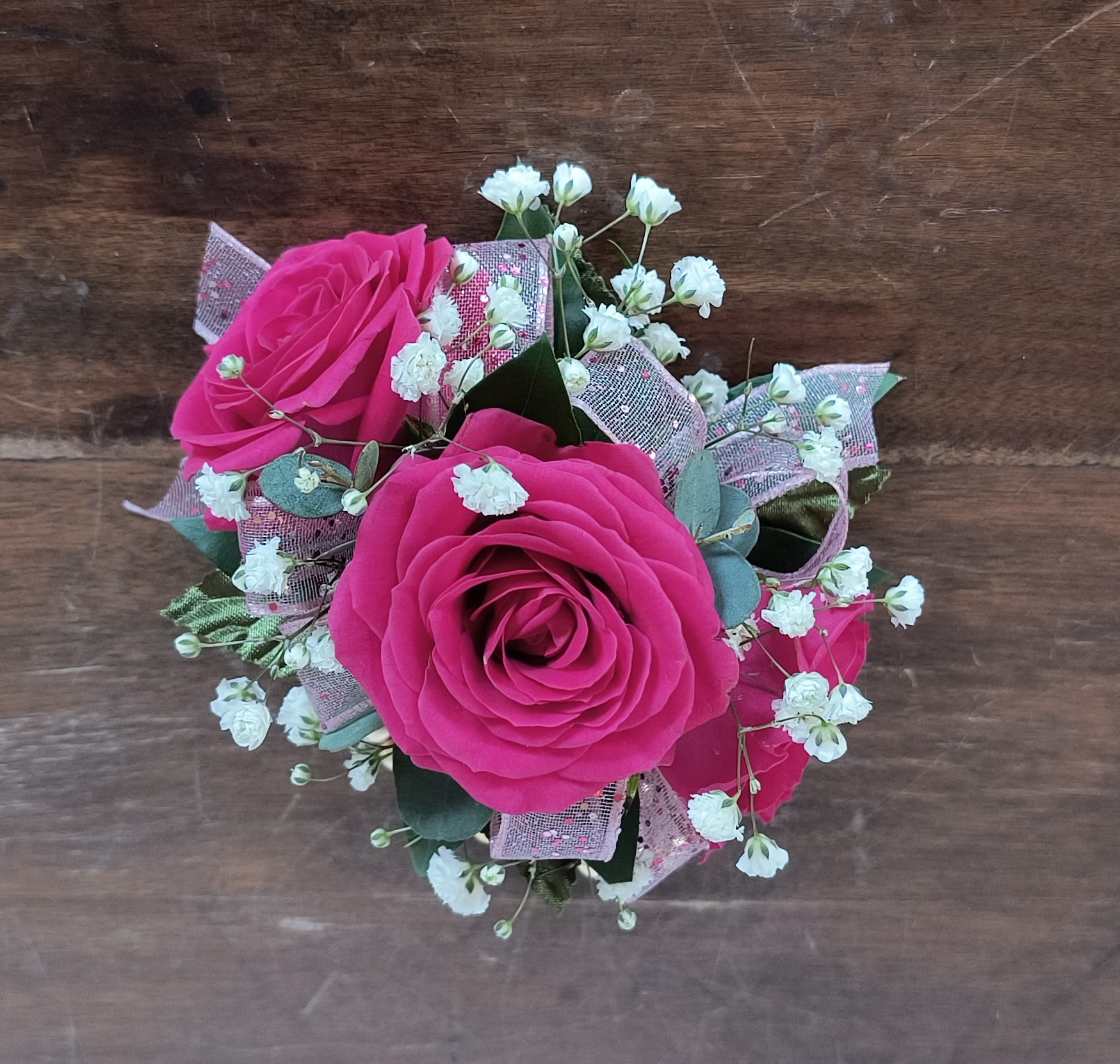Baby Doll Wrist Corsage - Fuchsia spray roses and baby pink ribbon accented with eucalyptus and baby's breath make this a fabulous feminine choice.