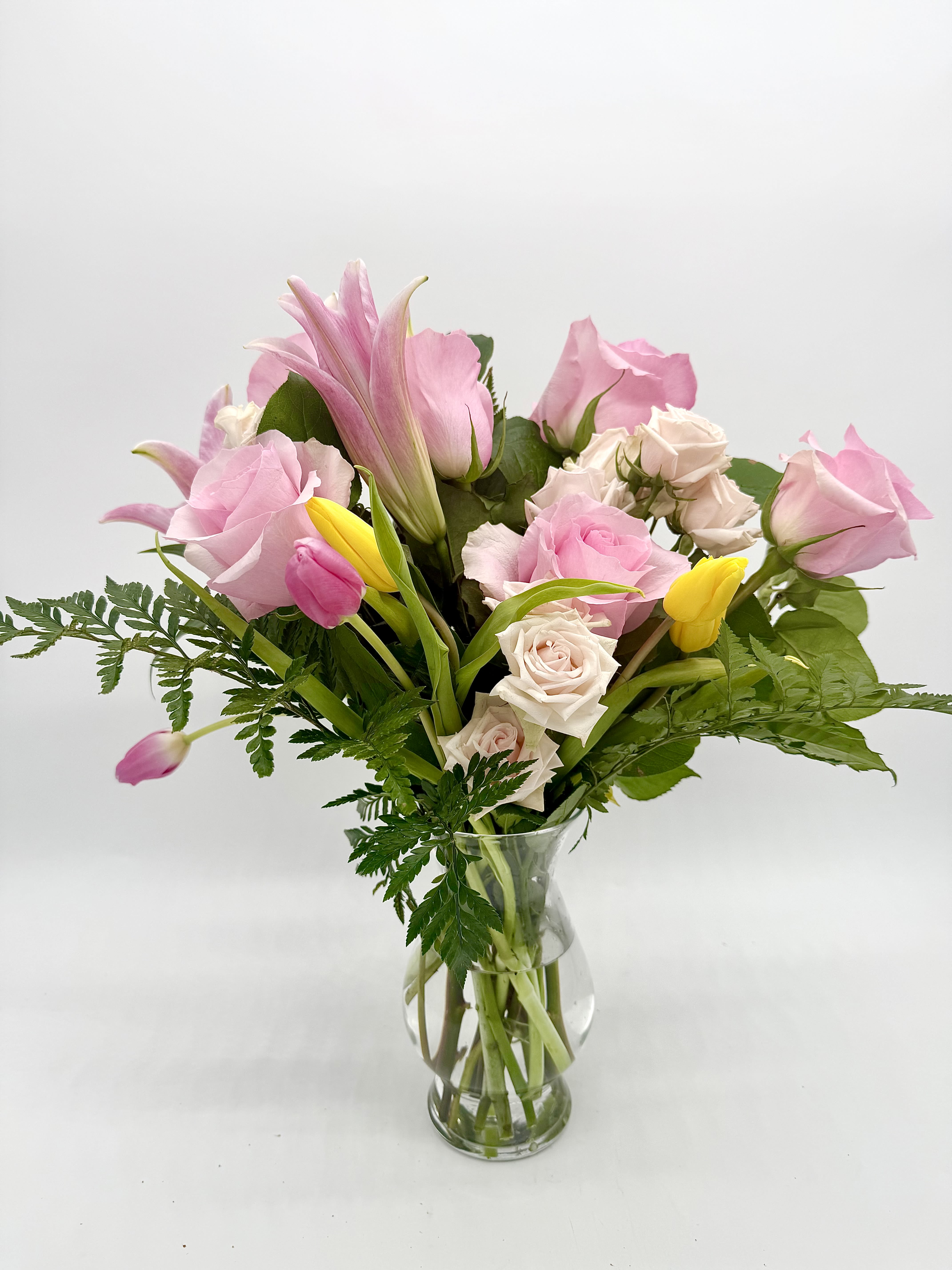 Mother’s Day Vased Arrangement Mother’s Day Vased Arrangement - A beautiful blend of seasonal flowers and soft-colored roses, thoughtfully arranged in a clear glass vase. This ready-to-display design is the perfect way to show love and appreciation on Mother’s Day—elegant, timeless, and made to brighten her space.