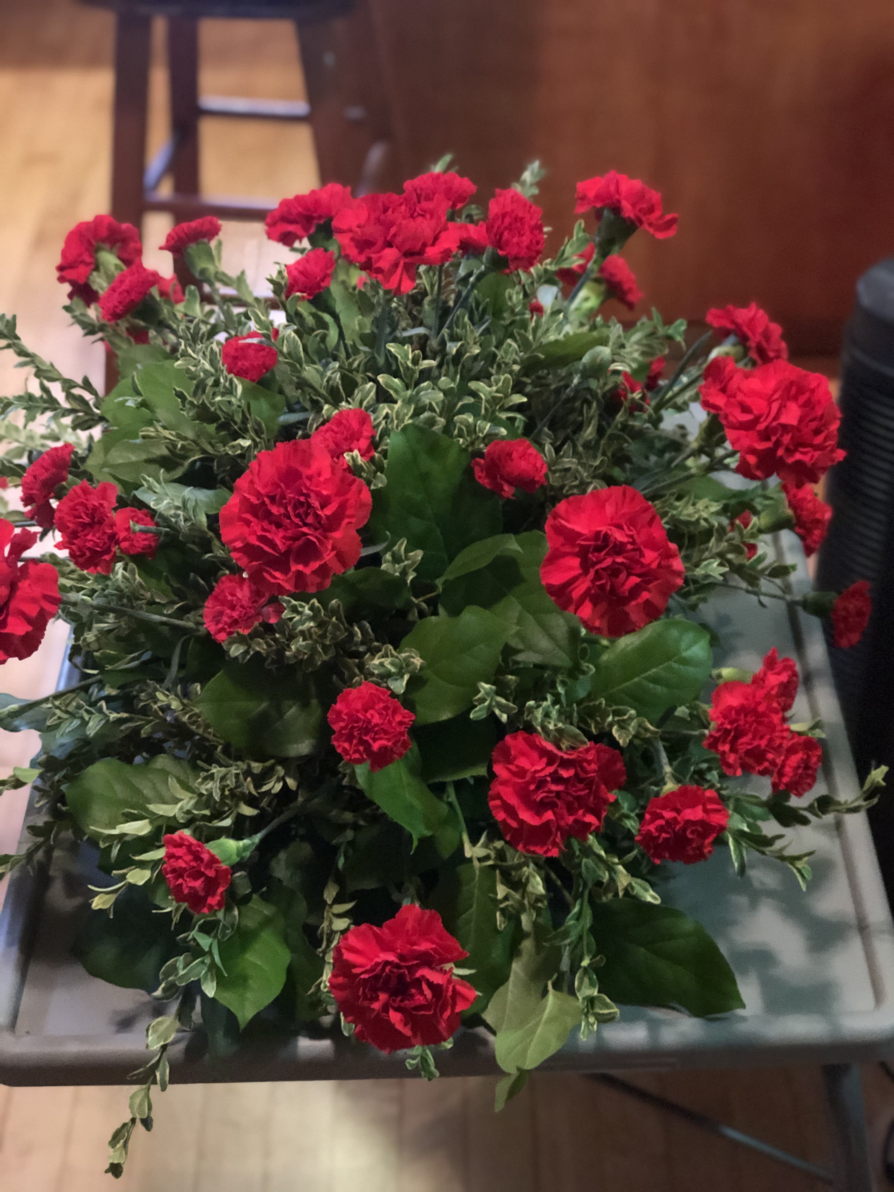 Devotion Casket Spray - This classic half-couch spray of brilliant red carnations makes a striking and dignified statement. Radiant red carnations and miniature carnations accented by fresh greenery arrive in a lovely spray. Any color can be used. leave color choice in notes on order.