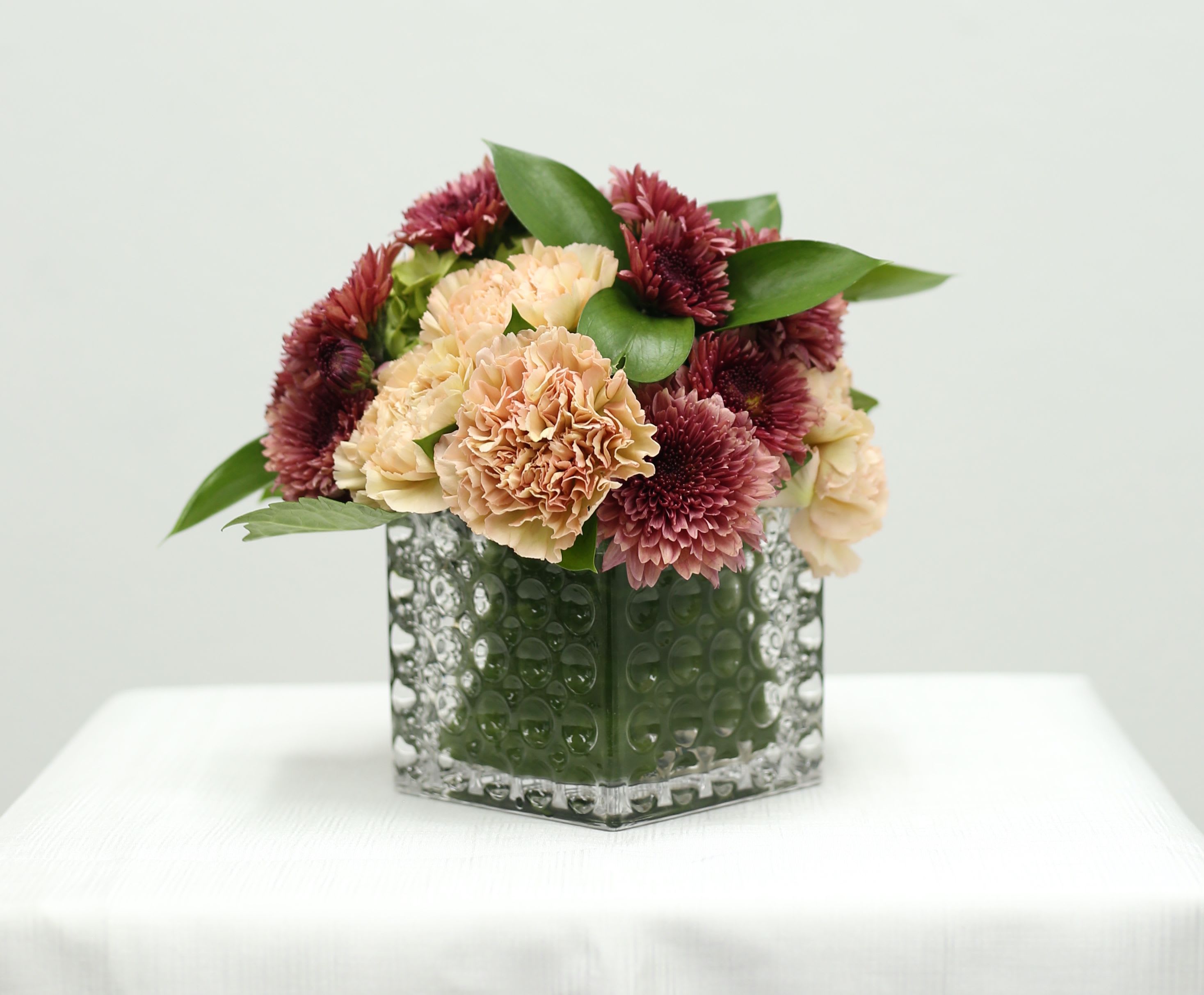 Vintage Blooms Vintage Blooms - Bring a touch of warm beauty to any space with this stunning floral design. Featuring a harmonious blend of peach and deep burgundy blooms nestled amongst fresh green foliage.