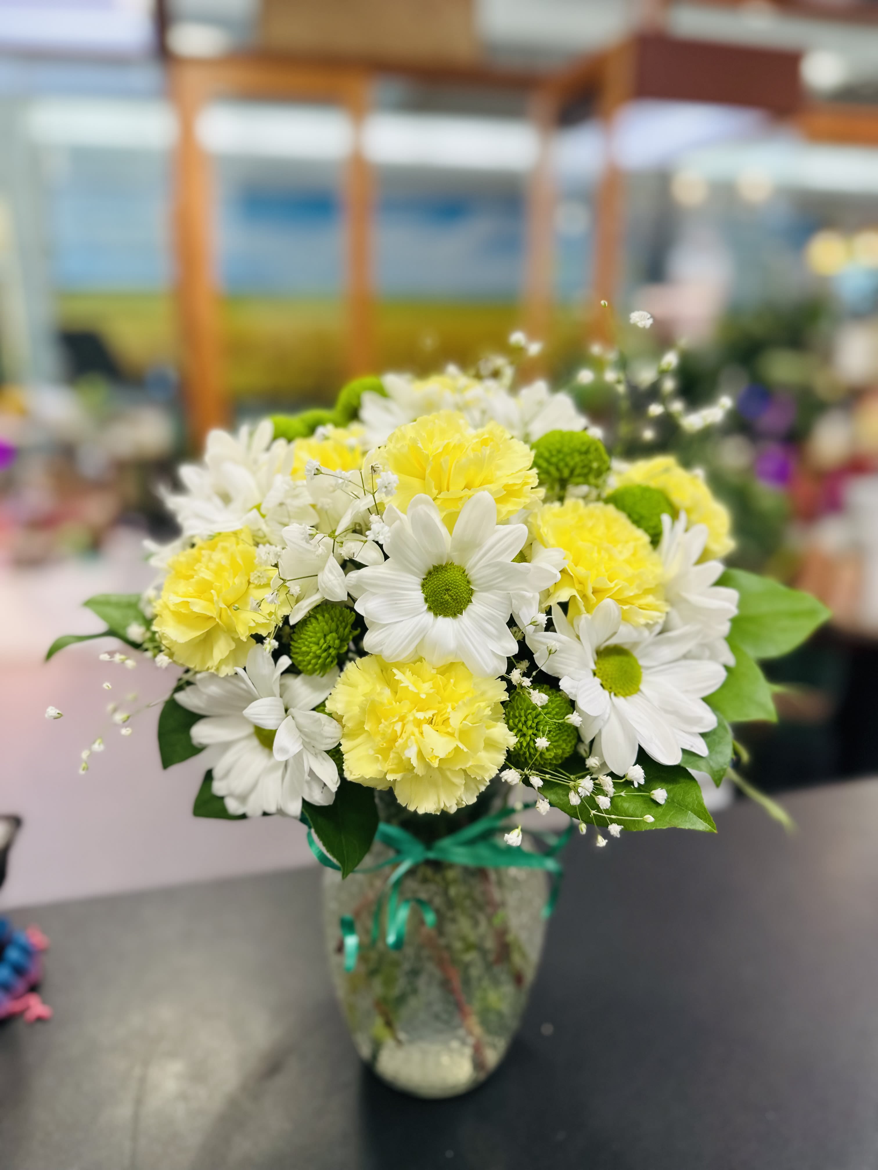 Come Around with Smile - These spunky blooms are just what they need to brighten their day! Gorgeous red Daisy and Carnations  are the perfect  gift to send to the one who's always on your mind and in your heart. Say &quot;I love you&quot; by sending this lovely arrangement and fresh greens delivered in a beautiful spring garden vase. Love always. 