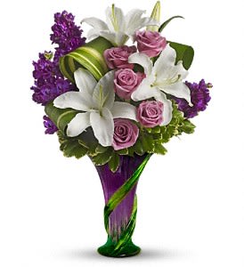 Teleflora's Indulge Her Bouquet - Go all out for Mom with luscious lilies and roses in a spectacular hand-blown art-glass vase sculpted with a stylish climbing vine motif. It's a breathtaking gift she'll love forever - and love showing to her friends.  The stunning bouquet includes white lilies, lavender roses and purple stock accented with assorted greenery.Delivered in a contemporary hand-blown purple art-glass vase with a green climbing vine motif.  Approximately 13 1/2&quot; W x 20&quot; H  Orientation: One-Sided  As Shown : T11M200A Deluxe : T11M200B Premium : T11M200C