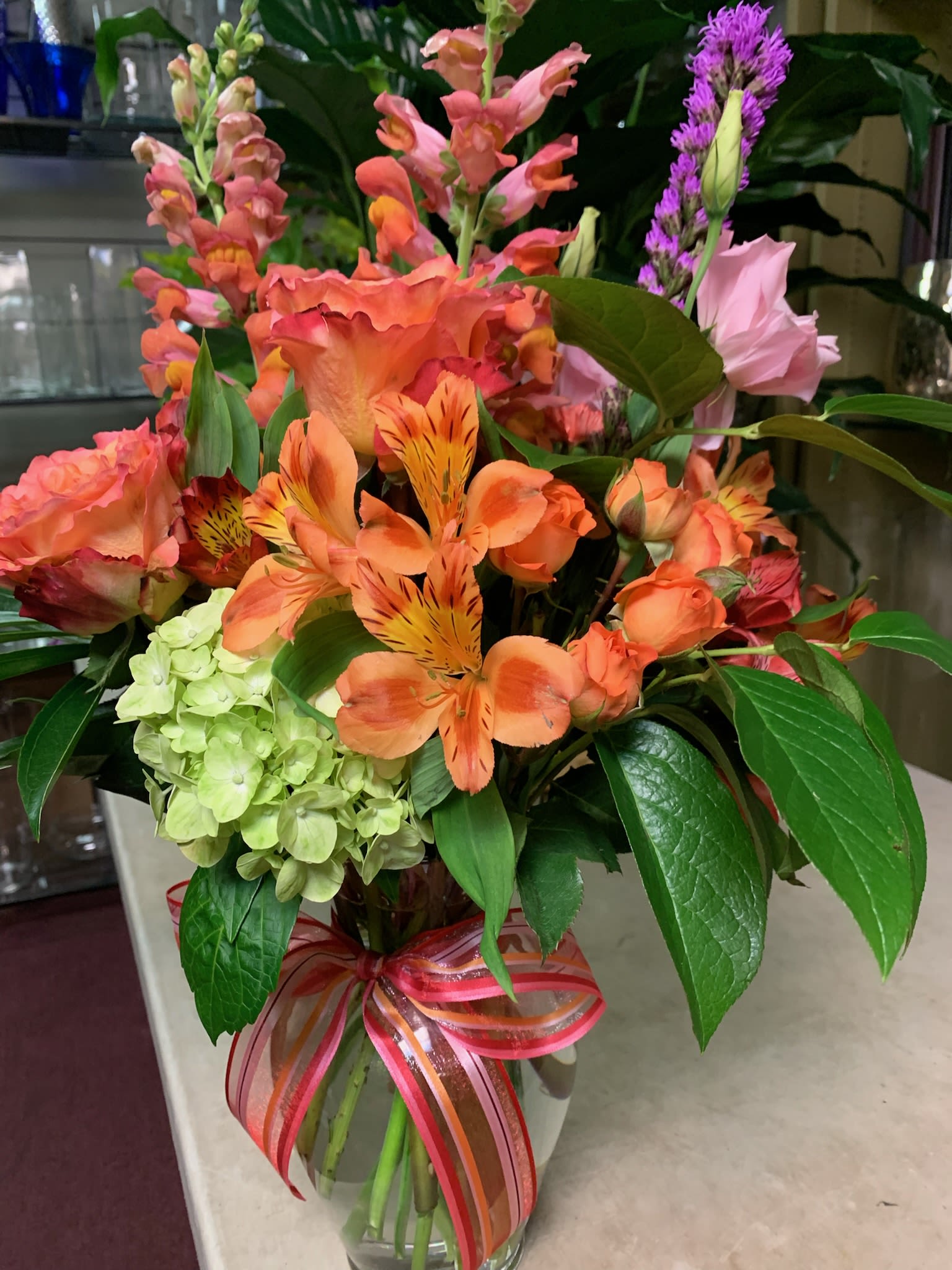 Colorful mixed bouquet in a glass vase with a ribbon bow