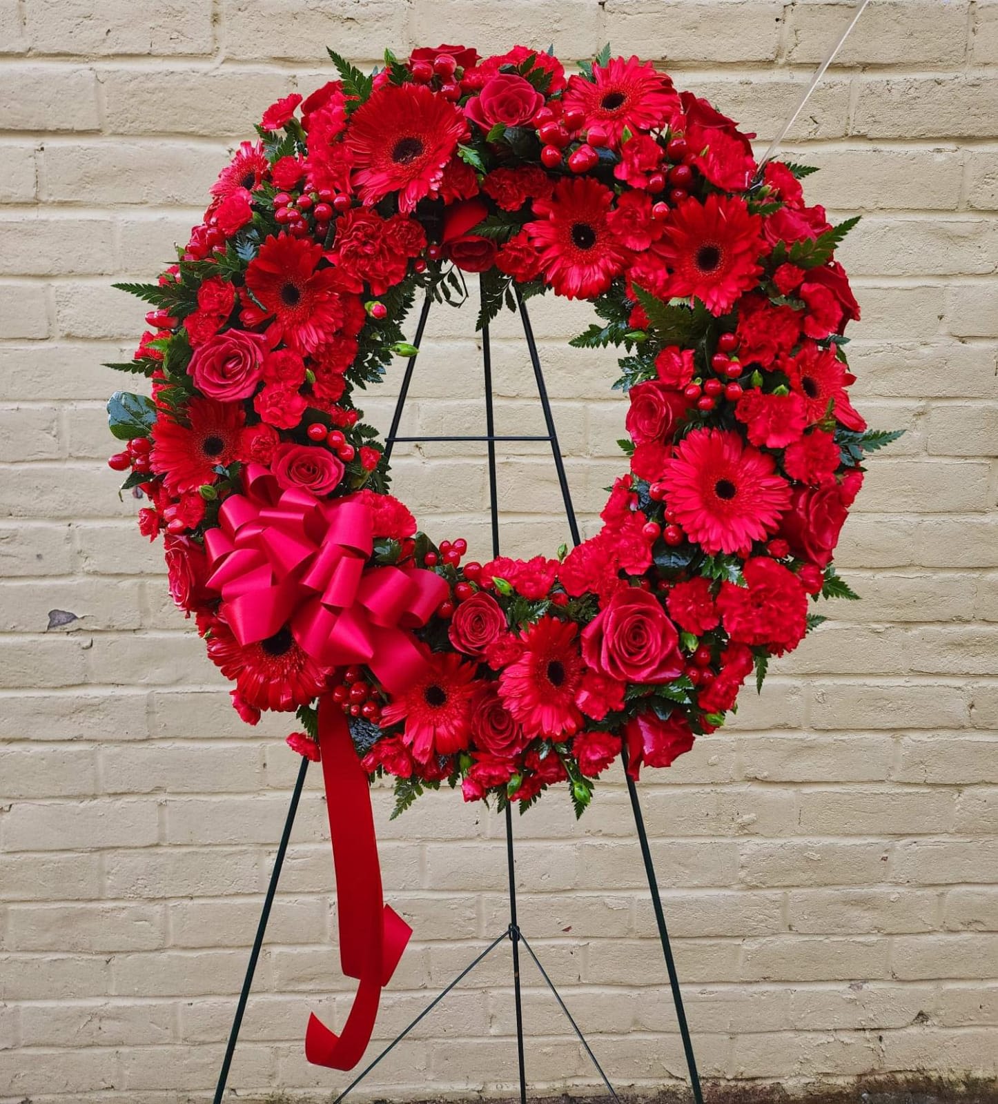 Crimson Tribute - This elegant arrangement of deep red blooms, symbolize respect, love, and remembrance for those who have passed. Its vibrant red hues evoke both honor and affection; a heartfelt tribute to loved ones no longer with us.