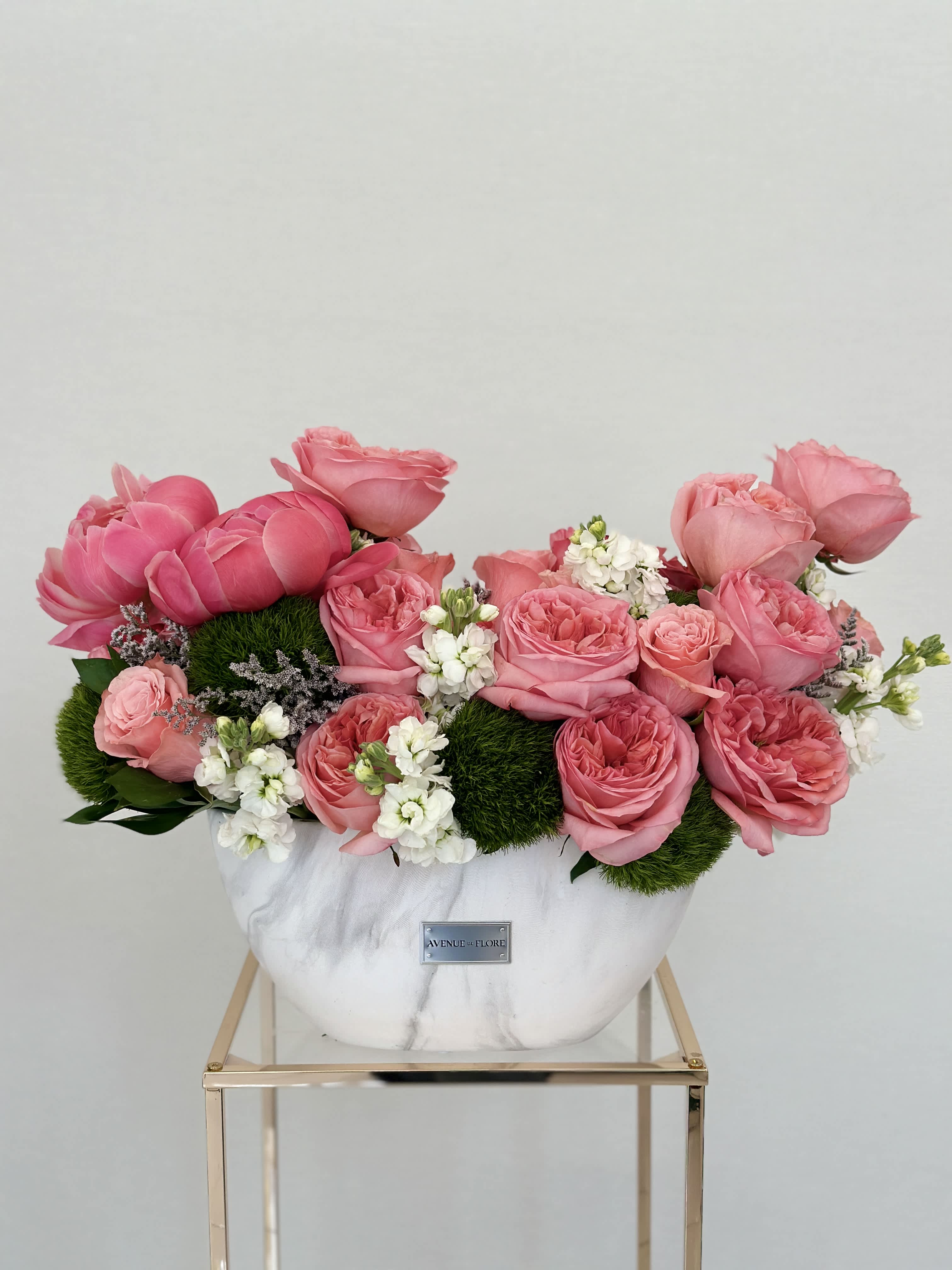 Coral Grace - Let the fragrance of garden roses and peonies whisk you away to a pink coral paradise. The sleek vase provides the perfect canvas for the vibrant hues of the blooms to take center stage, creating a captivating focal point that elevates any room.