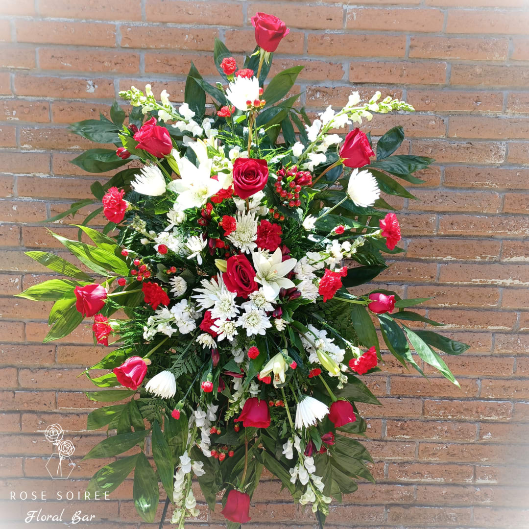 Dignity Standing Easel - Red and white tribute, this funeral spray will convey love and dignity. Featuring a variety of white flowers, vibrant reds and lush greenery this elegant funeral standing easel brings a feeling of love and comfort to those grieving a loved one.