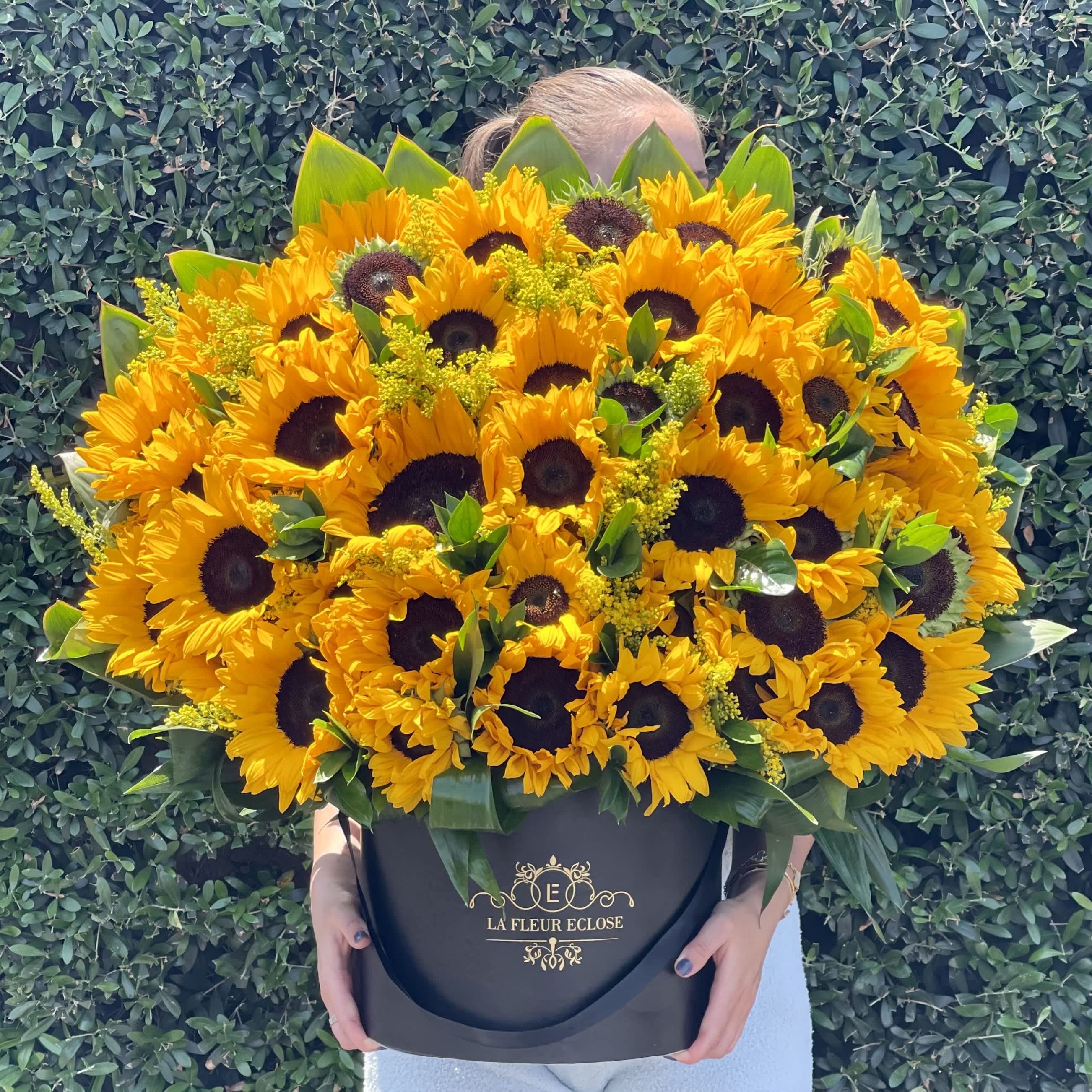 Sunflower Dream - The flower arrangement consists of vibrant sunflowers placed elegantly in a sleek black velvet box. The golden petals of the sunflowers contrast beautifully against the dark velvet background, creating a striking visual impact. The black velvet box adds a touch of sophistication and luxury to the arrangement, making the sunflowers stand out even more. This combination of bright sunflowers and the rich black velvet creates a stunning and dramatic display that is sure to catch the eye and evoke a sense of beauty and elegance.
