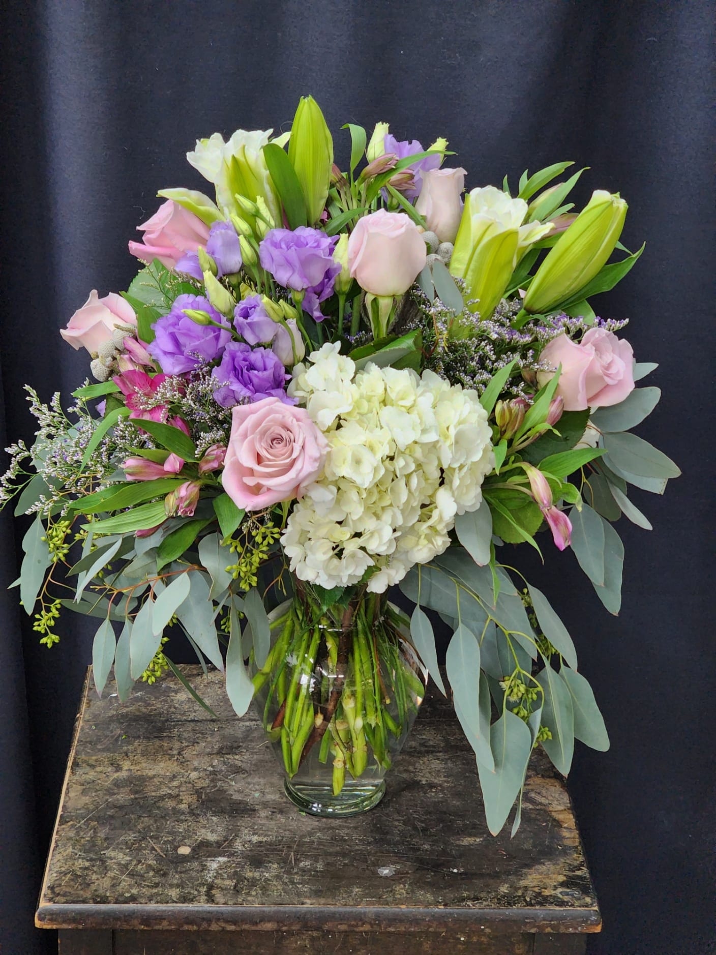 Designers Choice Luxury Blooms  (Images are Examples) - Premium Seasonal blooms like peonies, Ranunculus, Anemones, Garden Rose and  so many more. Arranged in a colored glass vase or ceramic container. A more contemporary design feel with Curly will branches, Aspidistra leaves, or Fatima leaves this arrangement will WOW every time. Flowers and design will vary with every order. If you have a color preference or season preference (ie; spring, summer fall) please leave it in the special instructions section when placing your order. 