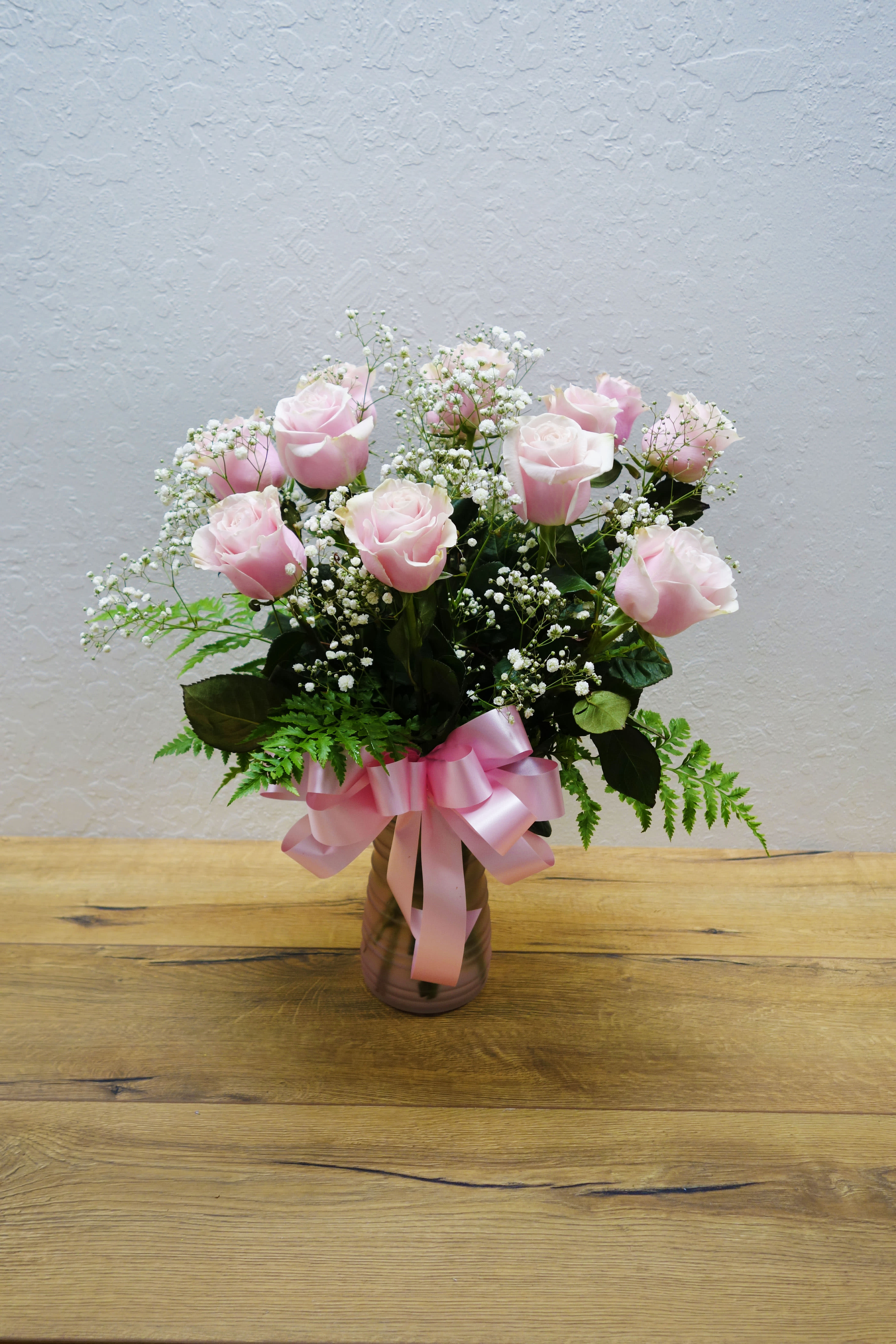 1 Dozen Pink Long Stem Rose 1 Dozen Pink Long Stem Rose - A dozen pink roses with variegated pittosporum and salal in a beautiful glass vase.  Orientation: All-Around Standard: 12 stems Deluxe: 18 stems Premium: 24 stems