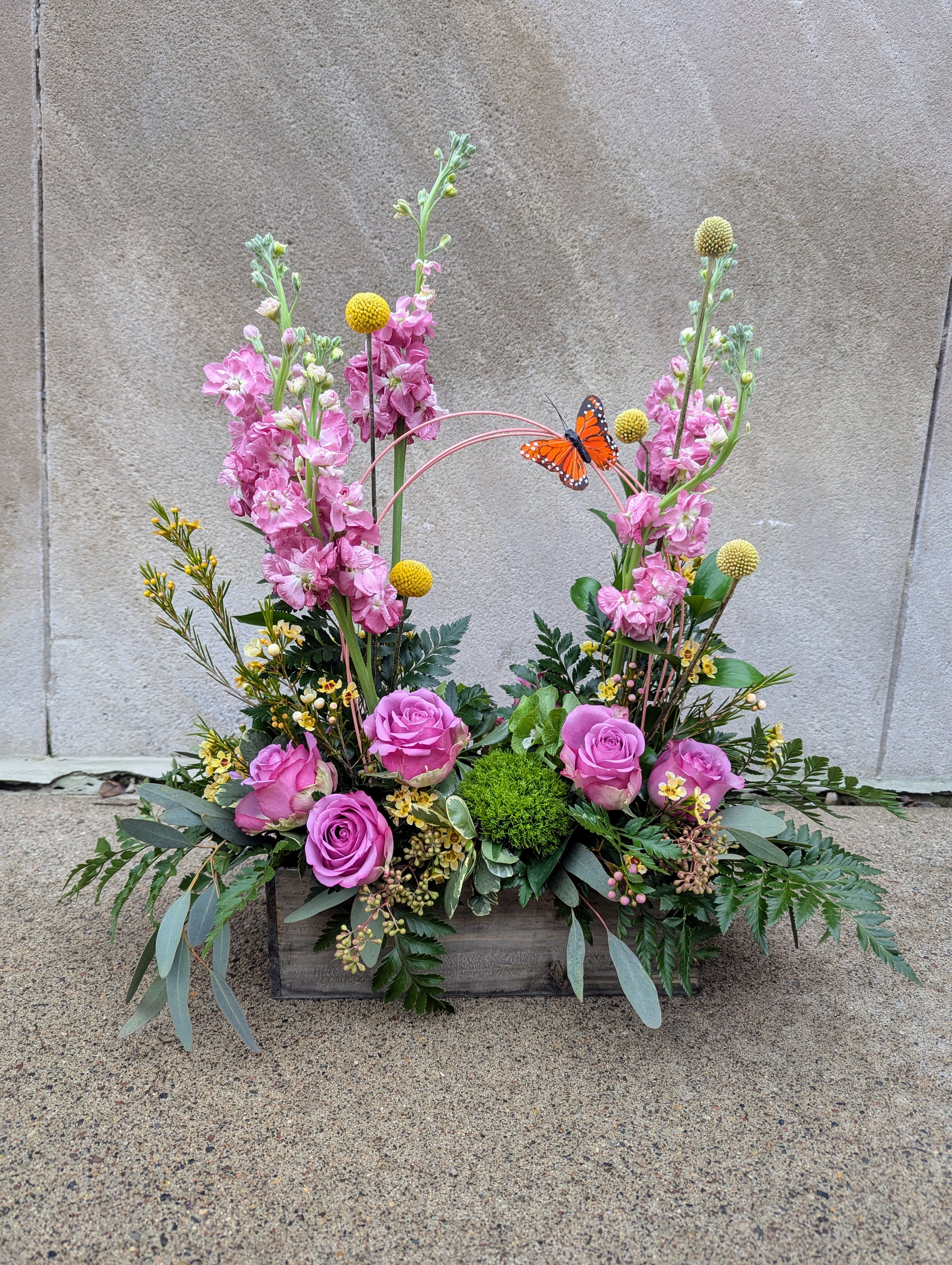 Best seller: Sunshine on the St Croix  - Designer's choice of seasonal cut flowers and accents to include bright and cheery flowers, pussy willow or curly willow, and midolinol arches. Designed in a wooden planter box.   Beautiful seasonal arrangement, hand-arranged and presented in a rustic wooden container.  This arrangement features a beautiful mix of botanical accents and feature foliages. The image shown is an indication of our signature Studio Louise Flowers design style. We will create an arrangement featuring the best of the season in a similar style and color palette.  Flowers are subject to seasonal availability. In the event that any of the flowers are not available, we will substitute them with a similar flower in the same shape, style and color. Standard size pictured. Stem count, container and packaging may vary. The container shown measures approx 5 inches tall.  Stillwater and St Croix Valley delivery.