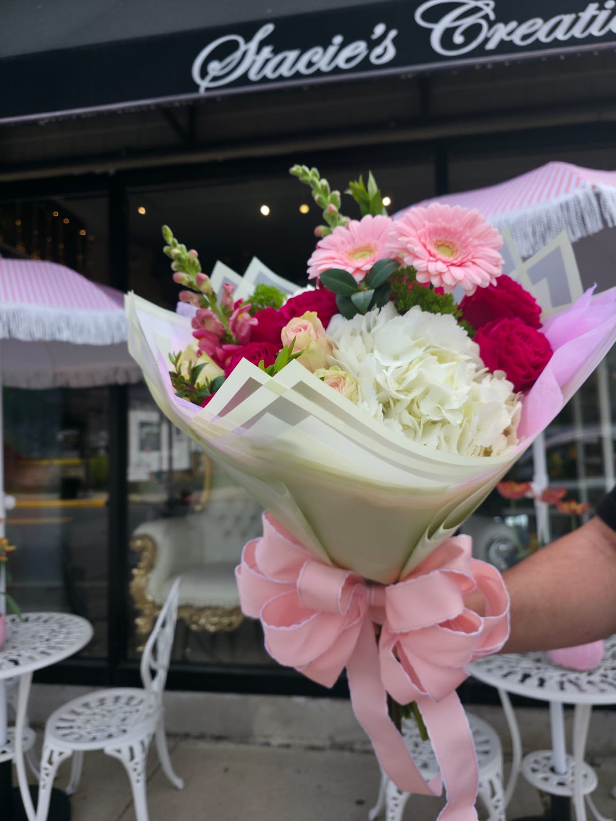 Stacie's Sweet Blossom - Bursting with color and charm, Stacie’s Sweet Blossom is a joyful mix of soft pink gerbera daisies, romantic roses in blush and bold hues, elegant white hydrangeas, and fresh greenery. Beautifully wrapped in delicate pastel tones, this bouquet is a radiant expression of love and appreciation—perfect for Mother’s Day or any occasion that calls for something extra special. 