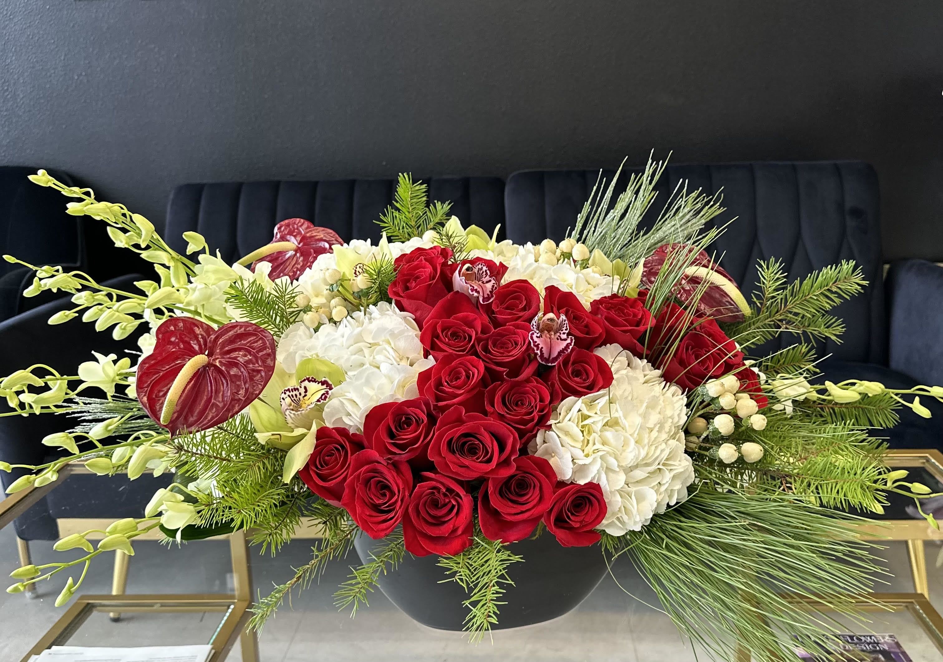 Happy Holidays! - Even if you are not into caroling, you can still bring joy to your neighbors, friends, and family! Send this  extravagant arrangement featuring red and white roses, white orchids,  anthuriums and pinecones to wish the recipient a happy holiday!  Arrangement Includes: -Fresh Cut Roses, Orchids, Hydrangeas, Anthuriums -Porcelain Vase -Custom Greeting Card -Care Instructions   