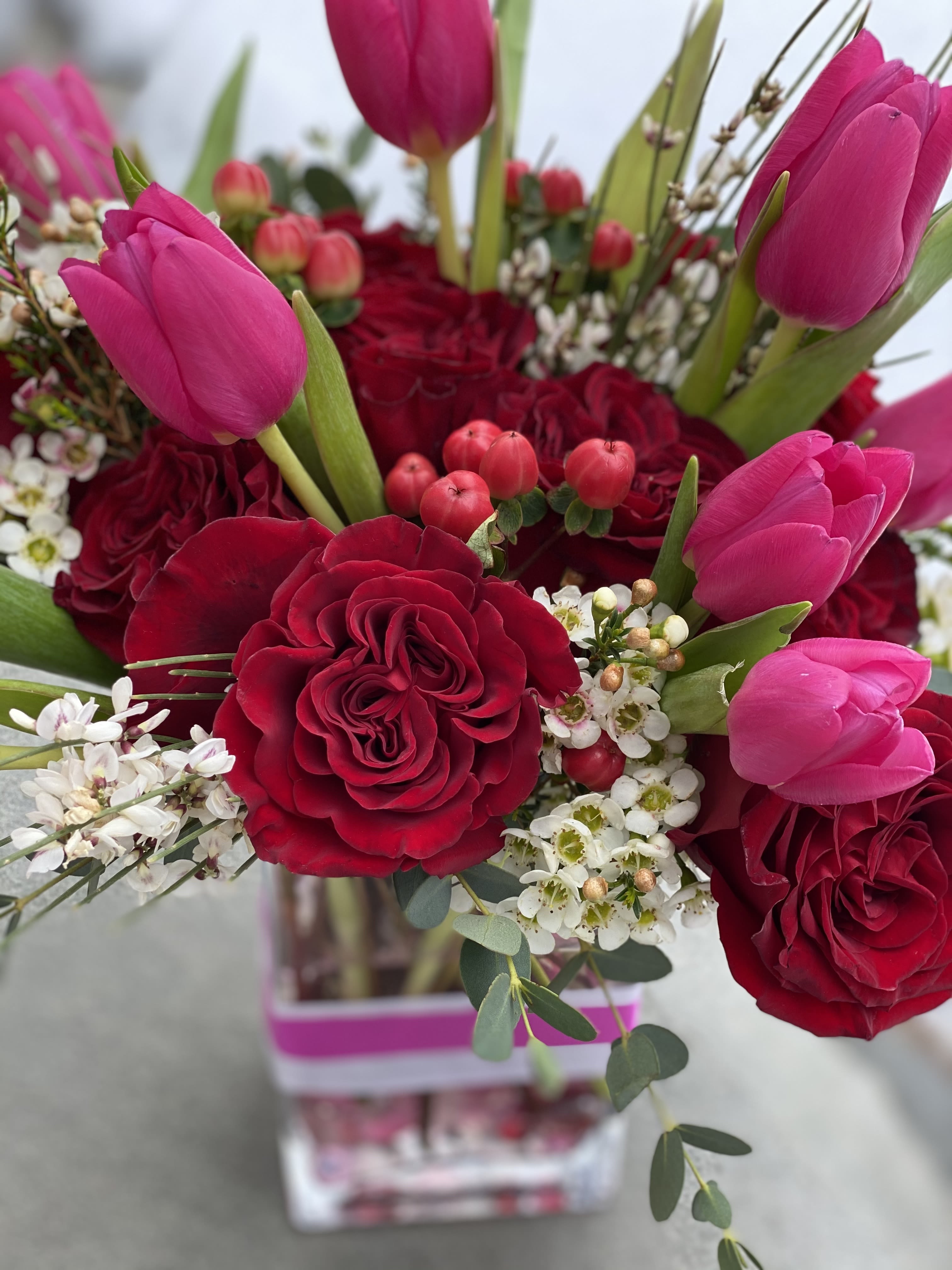 The Tulip + The Rose - We love tulips anytime of the year but on Valentines Day they pair so well with classic roses.  We use red roses and pair pink, white and/ or lavender tulips to the mix.  NOTE- WE ARE OUT OF HOT PINK TULIPS AND USING WHITES, REDS, PURPLES OR WHITES  Standard size- taller rectangle glass vessel- med height ( as pictured)   Deluxe - taller glass vased  Premium- Approx 10x 4&quot; vase- tall + terrific    