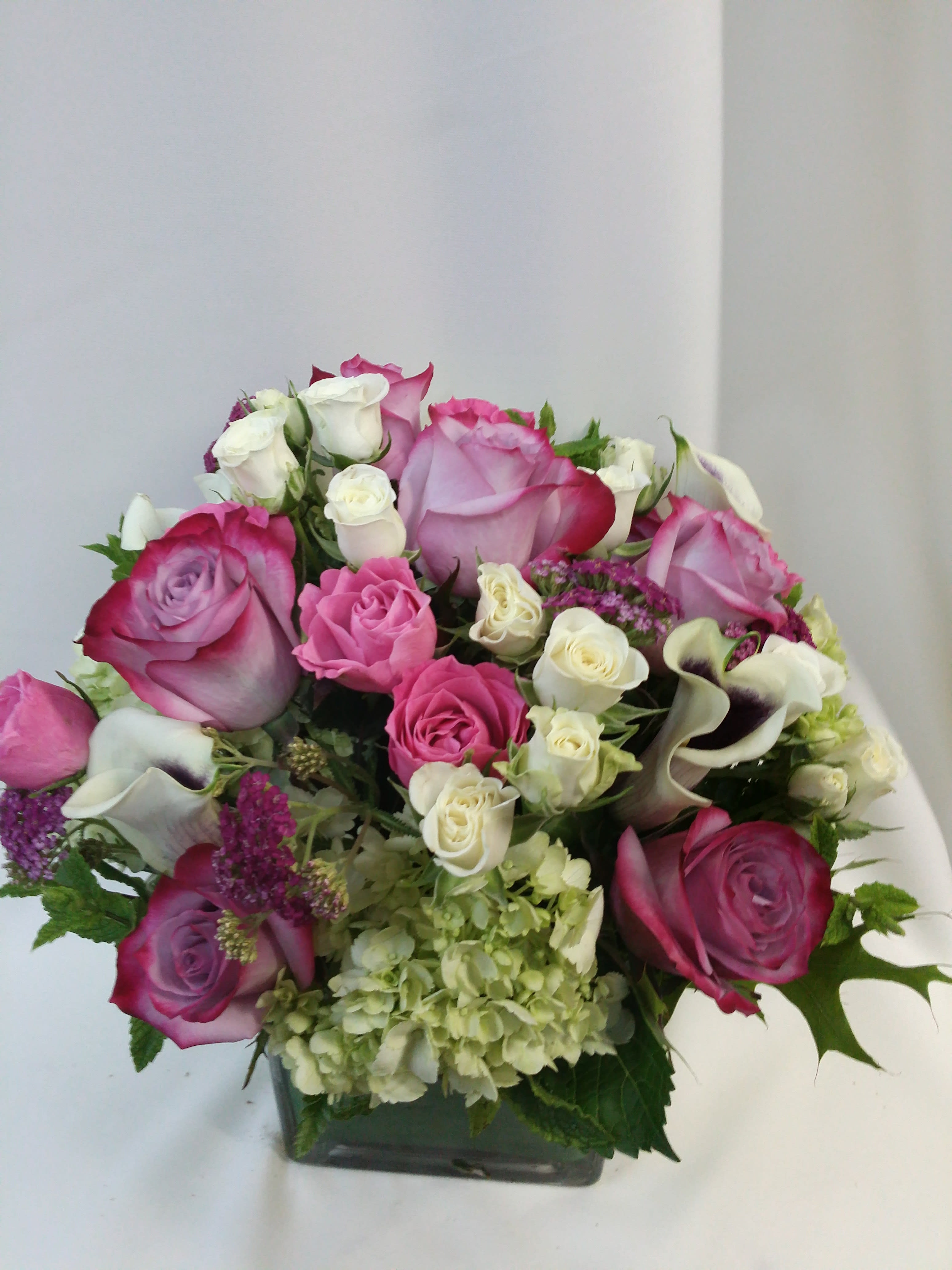 sweetness! sweetness! - Pink & Lavender roses, lime green hydrangea,and picasso calla lilies in a leaf lined square contemporary vase