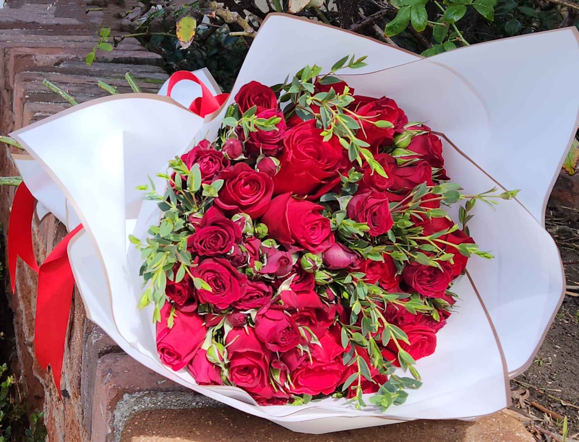 Hand Bouquet of Roses - A beautiful hand bouquet of long-stemmed roses wrapped in paper.  Standard Price - Dozen Red Roses Deluxe Price - Two Dozen Roses Premium Price - Starting price for custom bouquets