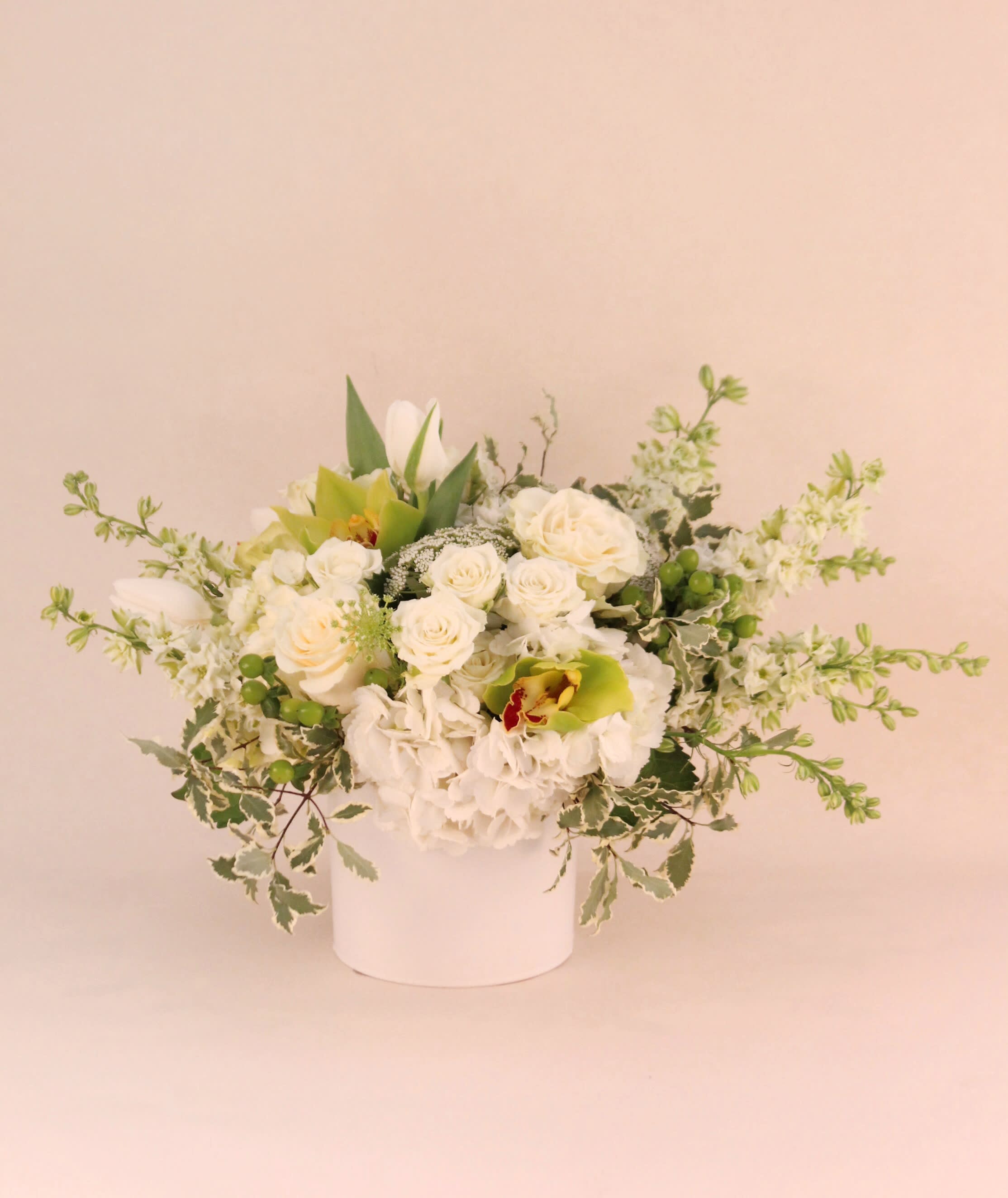 Pure Beauty - Stunning simplicity. A beautiful way of sending your love, appreciation and well wishes. This design is bloom heavy with delicate roses, hydrangeas, tulips, orchids  and variegated Italian pittosporum in a white ceramic cylinder vase.  Vase dimension: 5&quot; x 5&quot; Overall dimension approximately 10&quot; H x 18&quot; W