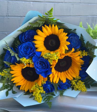 The Sunflower and Blue Rose bouquet - This handheld bouquet is created with beautiful royal blue roses and sunflower mix. ****Paper color will vary depending on availability****