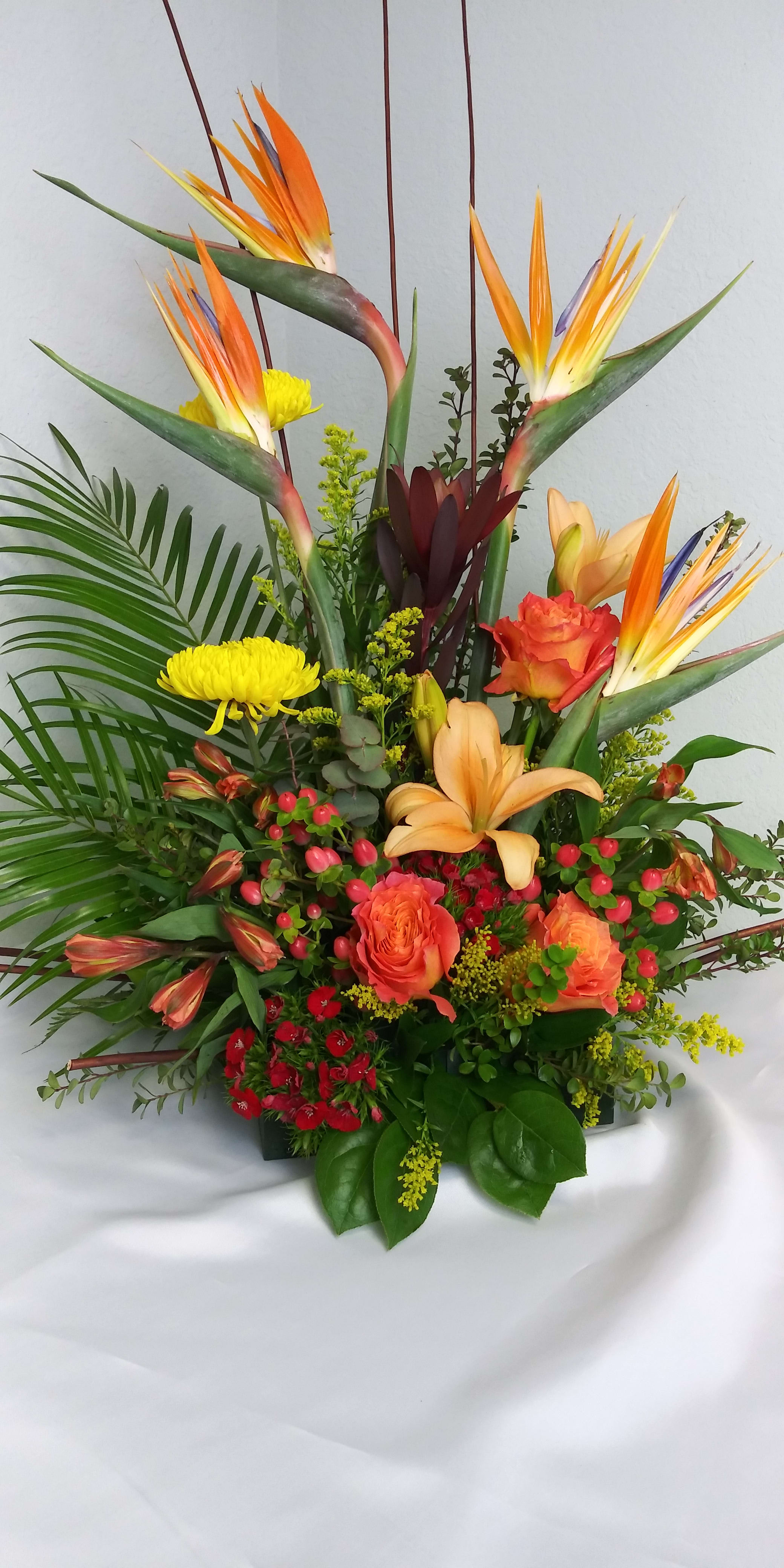 Paradise Flight Paradise Flight - Tropical arrangement in oranges, yellows and reds with bird of paradise, orange roses, hypericum berries, greenery and fillers. Shown at $100.00