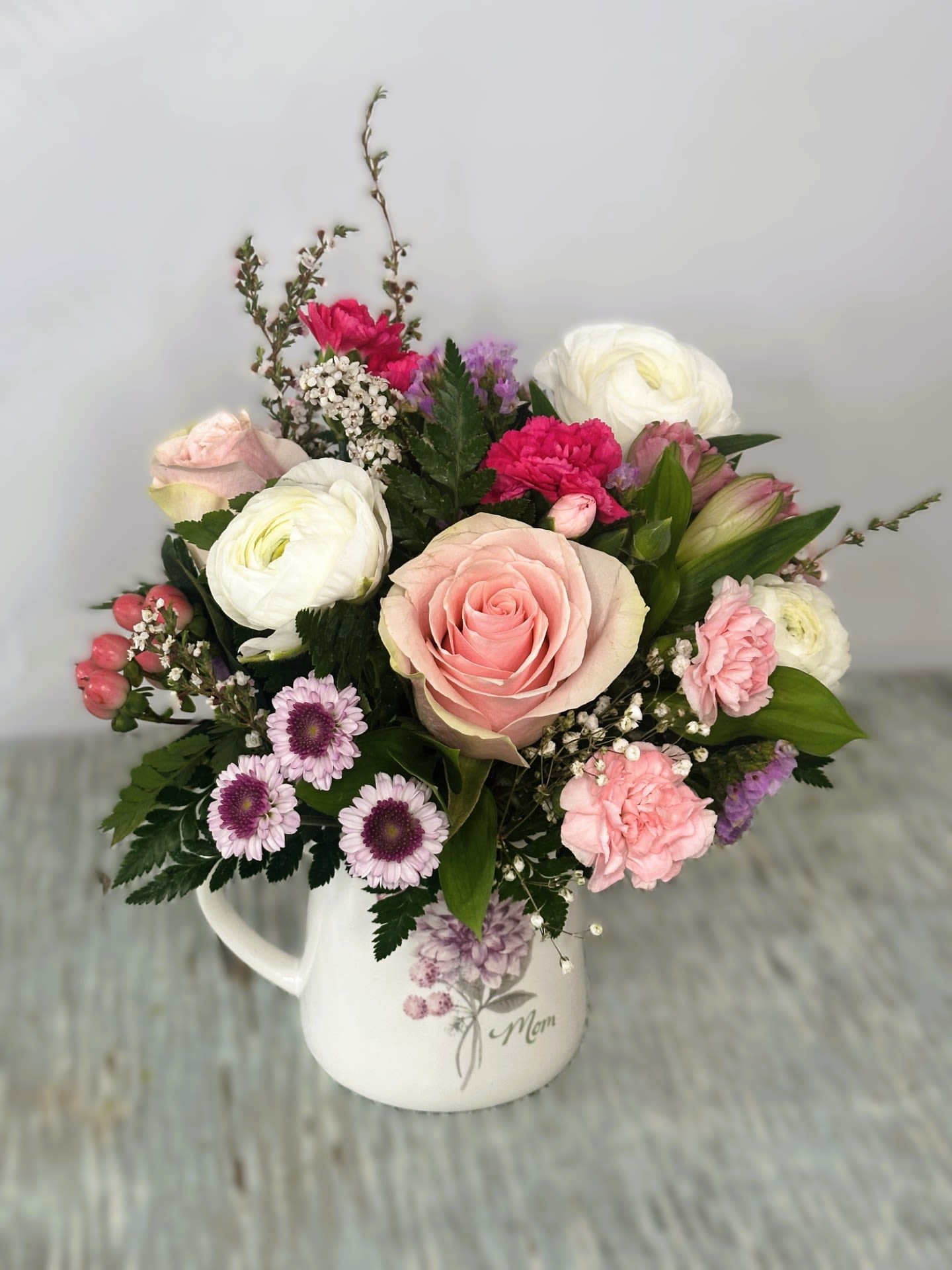 Mother's Day # 2 - Arrangement designed in an 16oz Ceramic mug with a lavender and pink floral bloom design on a white background. Has the message &quot;Mom&quot; under the bloom and a butterfly next to it.  Individually gift boxed. Arrangement measures approximately 11&quot;H X 8&quot;W. PLEASE NOTE: ARRANGEMENT WILL BE MADE AS SIMILAR AS POSSIBLE TO THE IMAGE YOU SEE. DUE TO HIGH DEMAND ALL FLOWERS MAY NOT BE AVAILABLE AND MAY BE SUBSTITUTED TO KEEP COLOR SCHEME AND STYLE AS SIMILAR AS POSSIBLE.