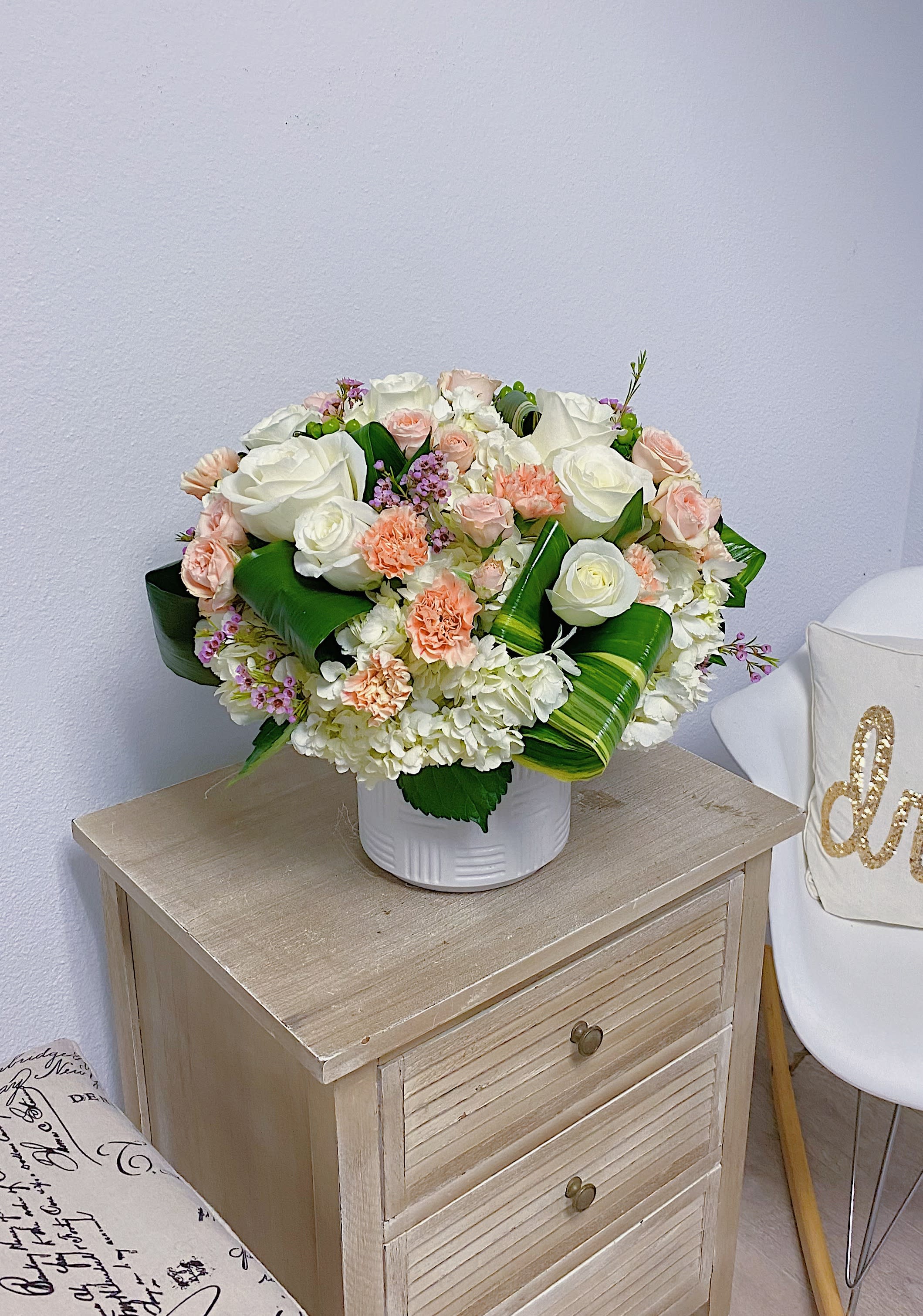 Peach and white  - Peach and white seasonal flowers in a vase with greenery and green leaves 