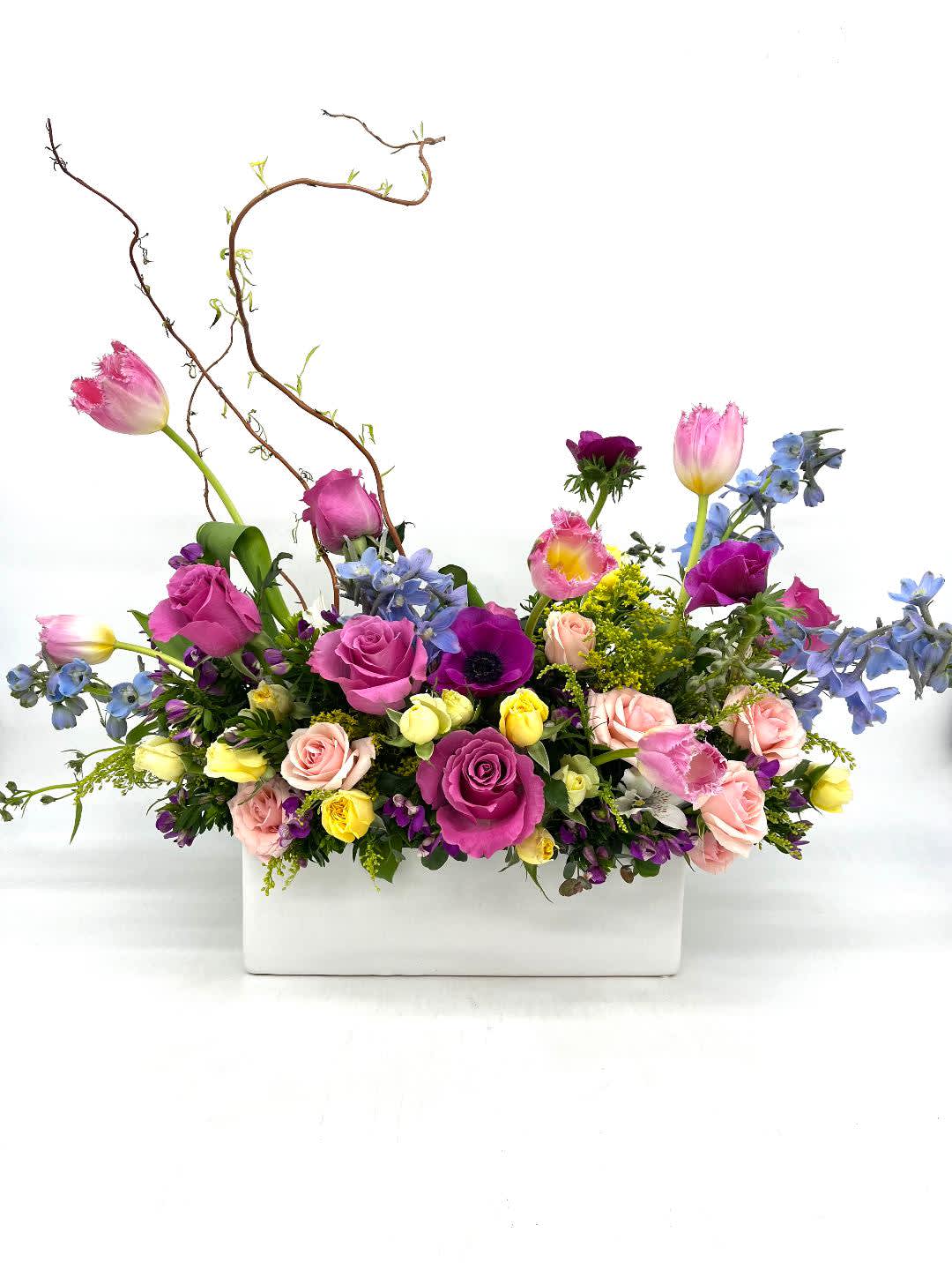 LF 395 Queen Bee LF 395 Queen Bee - This beautiful bouquet will surely delight the Queen in your life. Lovely spring blooms which include roses, delphinium, tulips, anemone, curly willow and an array of other spring mixes. All this beauty in a white ceramic container is perfect for a Queen. Orientation- All Around Approx Dim. 16" W x 12" H x 8" D