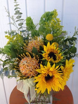 Sunglow Sunglow - bright and cheery arrangement with sunflowers and pincushions, eucalyptus, bells of ireland in a low glass vase.