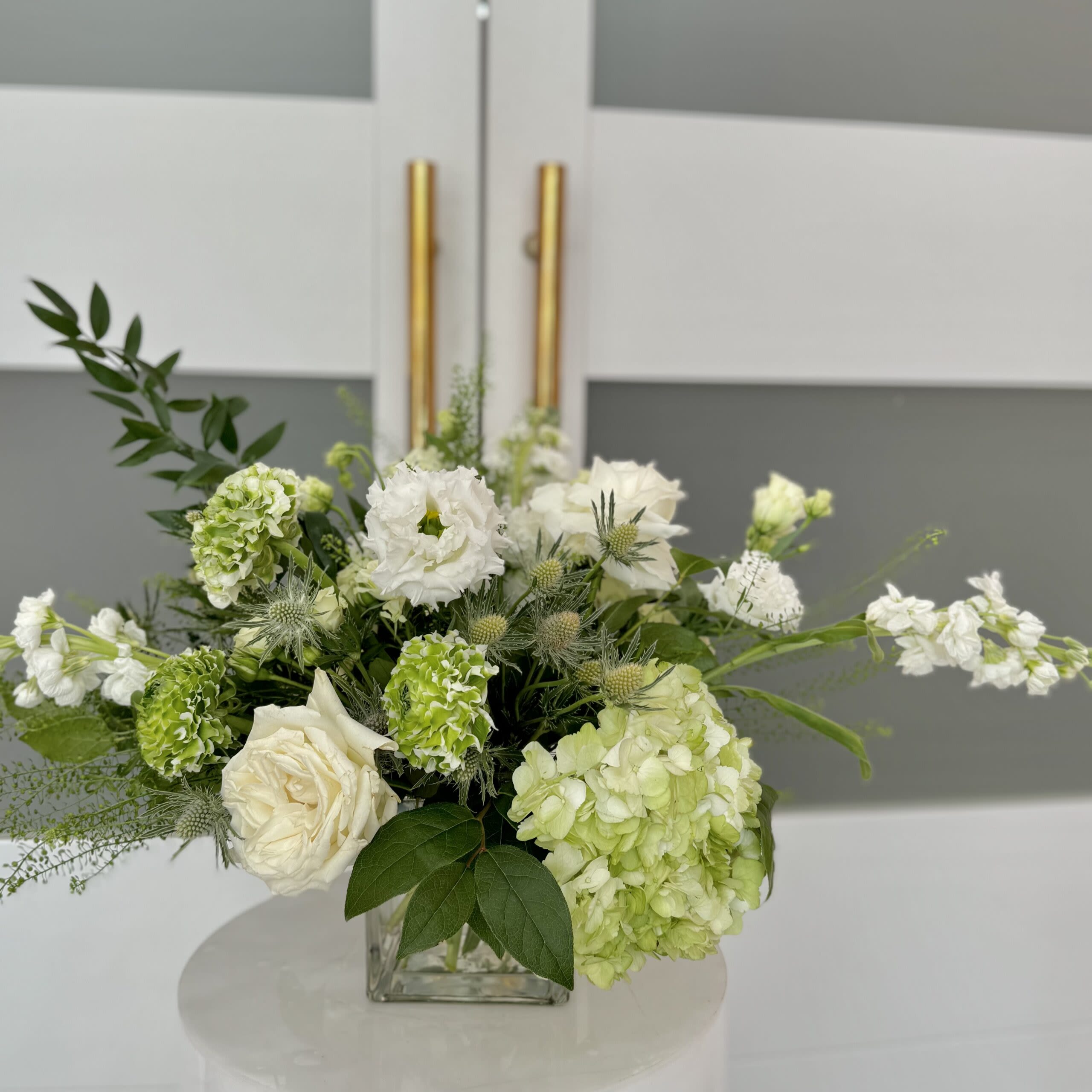 Green Mix Flowers - Assortment  of white and a mix of greenery on a clear vase.