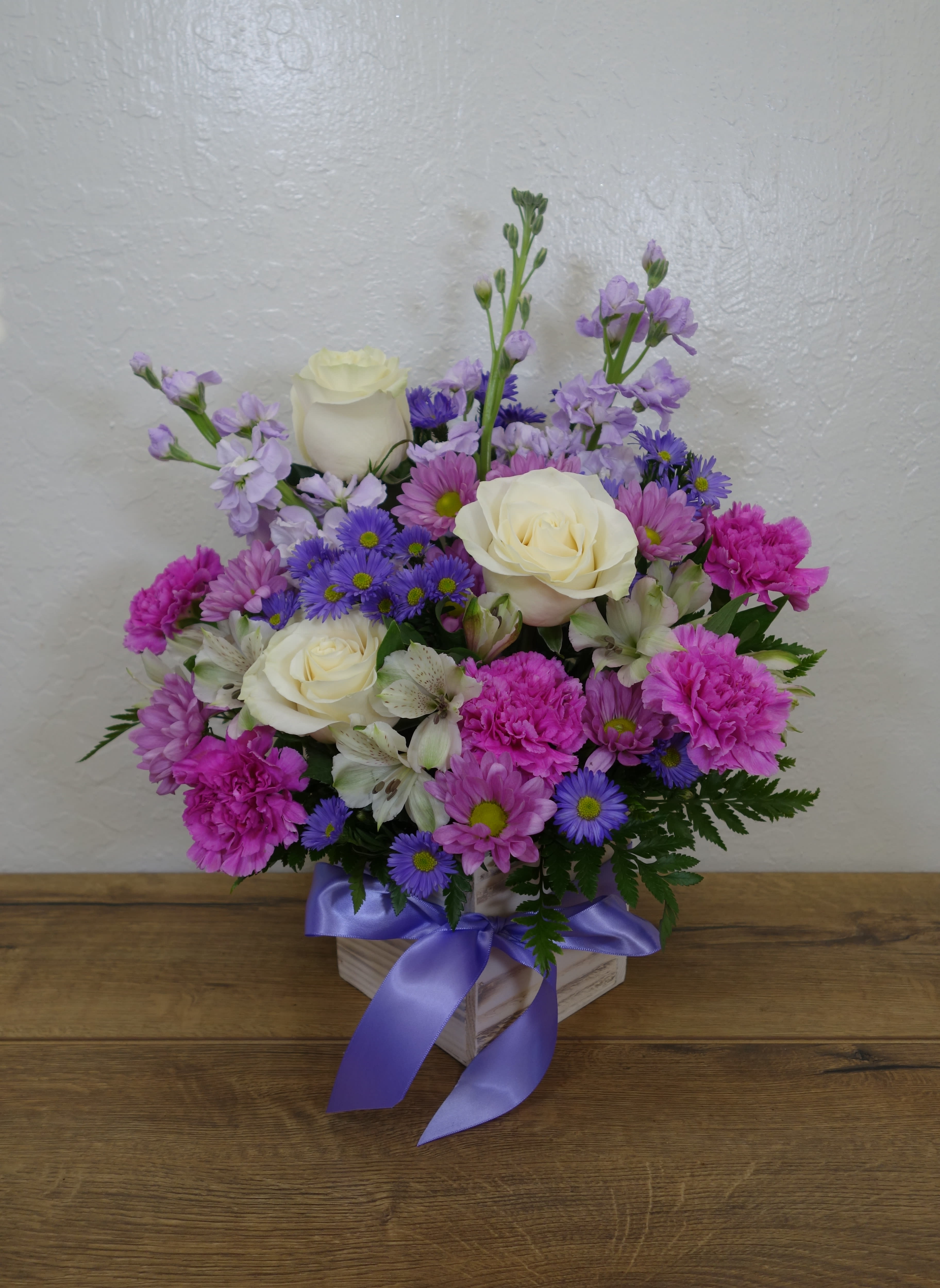 Miss You - No matter how close or far she may be, we're always thinking about her... Remember to call her and wish her a happy mother's day! This mother's day arrangement features roses, carnations, daisies, alstroemerias, stocks, filling flowers and mixed foliage in a wooden box.