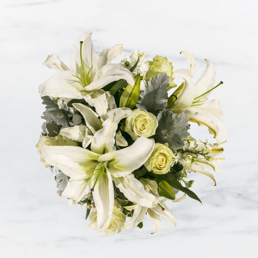 Sweet Thoughts by BloomNation™ - This arrangement includes white roses, white asiatic lilies, white stock, and dusty miller. Send your condolences with Sweet Thoughts by BloomNation™.   APPROXIMATE DIMENSIONS:10&quot; H X 11&quot; W X 11&quot;L