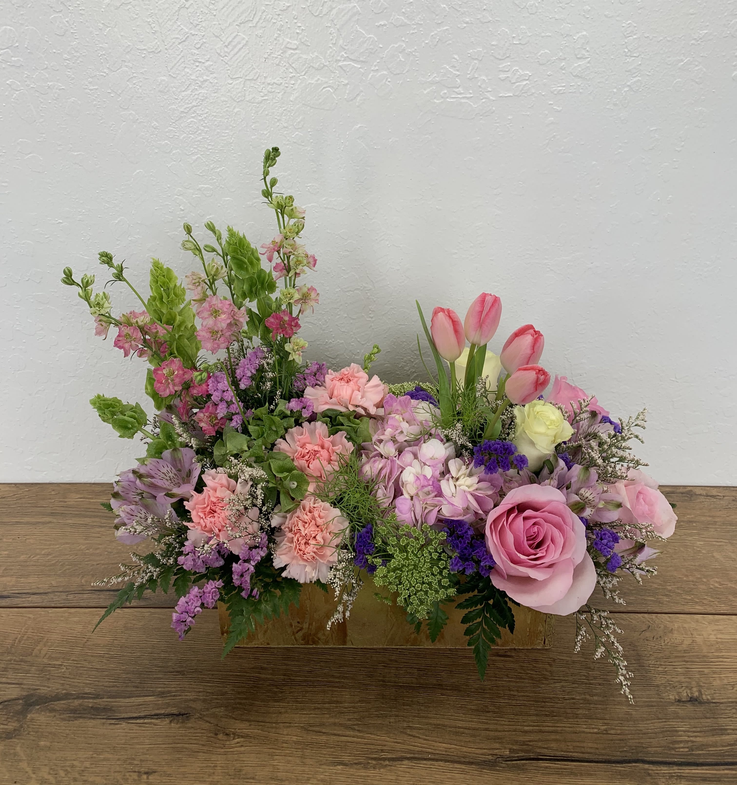 Secret Garden - Pink and Lavender - A secret garden lies within our imaginations, a sight to behold. This unique pink and lavender-colored arrangement features roses, hydrangeas, tulips, carnations, alstroemerias, statice, and mixed foliage.  Decorations may vary depending on store availability.  Deluxe (as shown) The arrangement is approximately 14&quot; H and 15&quot; W (Woodbox 12&quot; W)
