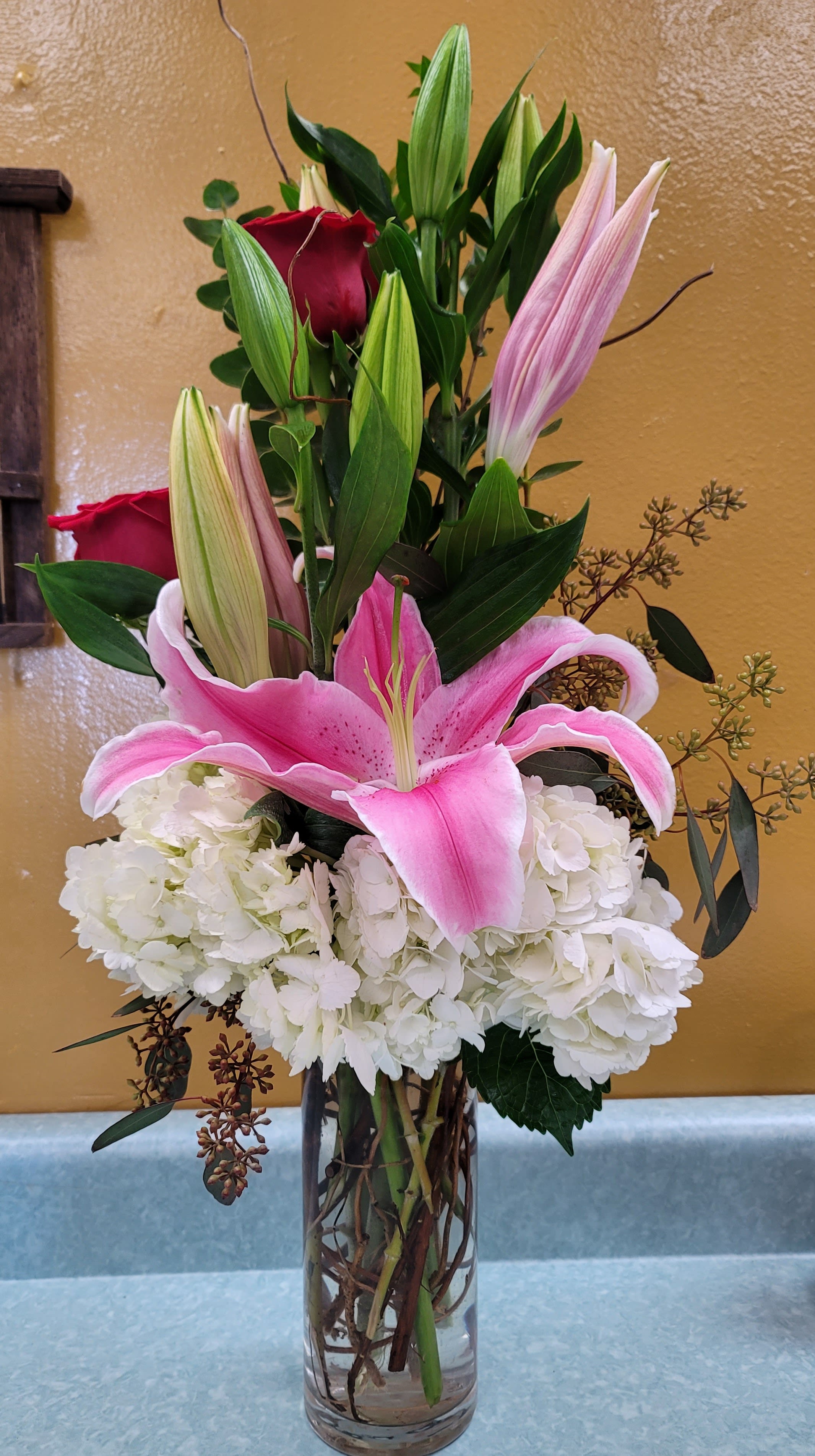 Lilly Rose by Xochitl Flowers EP - beautiful white hydrangeas, stargazer lilies and red roses in a clear cylindric vase WITH 2-4-6 ROSES, depending on the size.