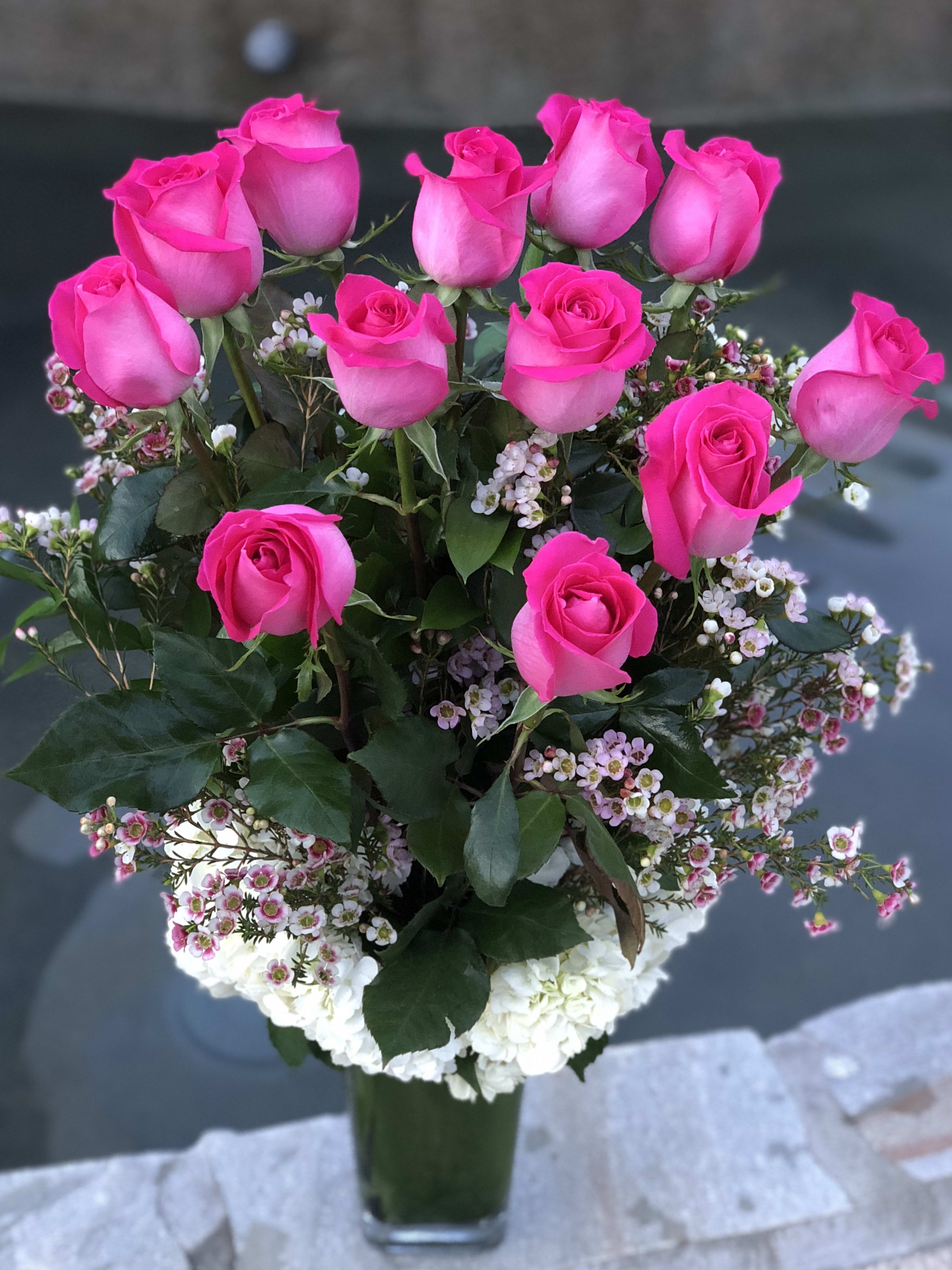 Pauline - Dozen Long Stem Pink Roses in a Vase - A dozen long stem pink roses ecuadorian imported roses on a bed of hudrangeas and exotic greens in a tall glass vase.   The photo shows Standard design.  Upgrade to Deluxe for 18 pink roses.  Upgrade to Premium for 24 pink roses. 