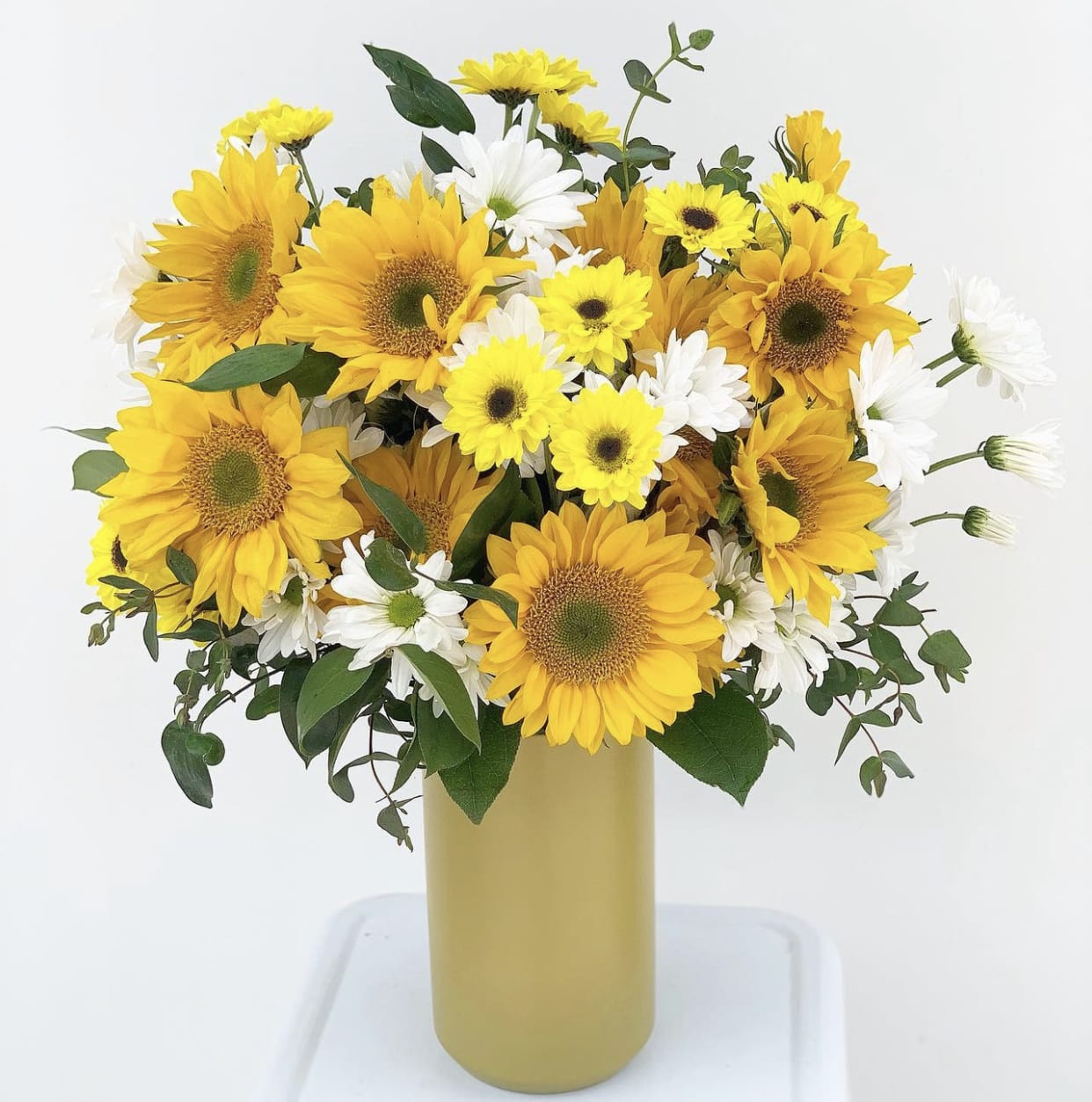 The Lennon The Lennon - Let the sun shine in this summer with this retro seventies throw back! Featuring yellow sunflowers paired with pops of cheery yellow, roadside daisies, and eucalyptus in a tall chartreuse vase, The Lennon is sure to bring a smile to anyone's face. Designed 360, it's perfect for gift giving or a summertime picnic.