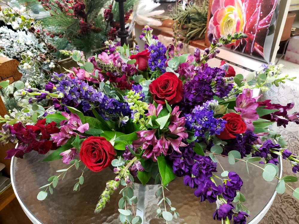 Array Of Purples  - Red roses compliment purple stock, purple larkspur, burgundy snapdragons and purple alstroemeria in a low container 