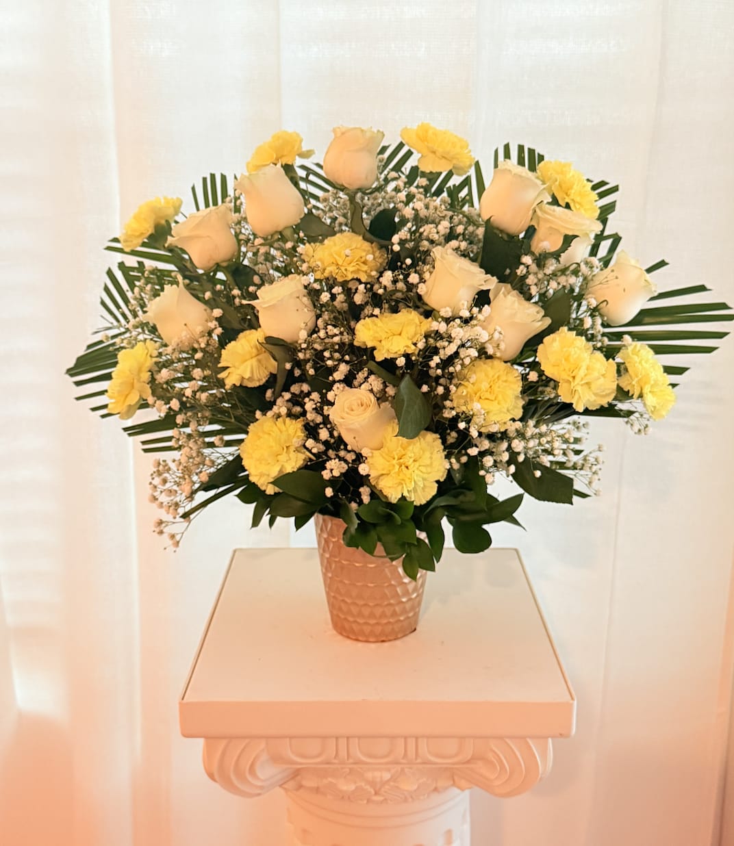 Sunlight &amp; Serenity Arrangement - Brighten their day with peace and cheer.  Our *Sunlight &amp; Serenity* bouquet blends gentle elegance with a touch of joy. Featuring classic white roses paired with sunny yellow carnations and cloud-like baby’s breath, this arrangement is finished with fresh tropical greenery and arranged in a textured gold ceramic vase. It’s a perfect gift for Mother's Day, sympathy, celebration of life, or simply to bring a warm smile.   **Includes:**  * White roses * Yellow carnations * Baby’s breath * Tropical fan palm leaves &amp; assorted greenery * Gold-textured ceramic vase (included)   **Approximate Size:** 20&quot; H x 18&quot; W  *Delivery available in Orlando, FL only*  *Hand-designed using fresh seasonal blooms*  A graceful floral embrace of light, love, and comfort.  