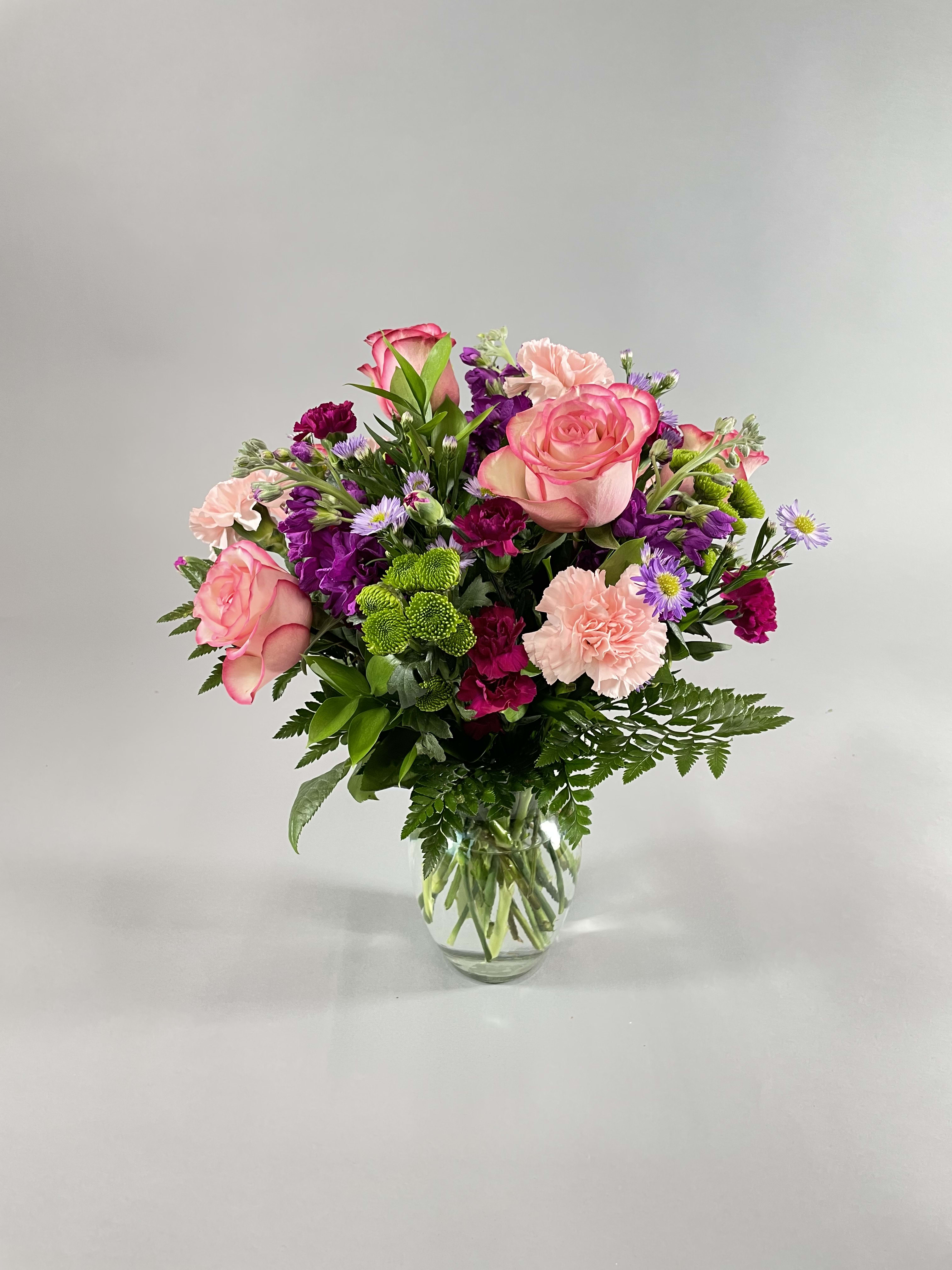 Soft Surrounding - Create a warm and inviting atmosphere for your loved ones with our exquisite arrangement of soft pastel tones. This charming display features a delightful blend of roses, carnations, stock, and pompons that is perfect for any occasion. Whether you're looking to surprise a loved one or decorate your own home, this floral arrangement is sure to delight you.