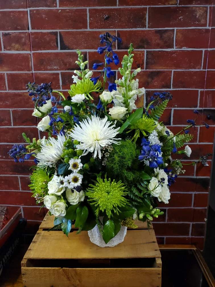 Honored to Know You - An all around flower arrangement designed with fresh flowers to include blue delphinium, white spider mums, green spider mums, trix, green hypericum, Yin yang, white spray roses and white snap dragons in a mache  * Some stages of flower life may vary. (Example: Lilies may be more open than imaged.) Flower shortages and product availability means that some substitutions will apply. Value will always be filled. This bouquet might include eucalyptus amongst the greenery. It may be toxic to pets including but not limited to Cats and Dogs if digested.