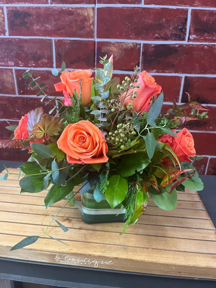 Small But Mighty - Orange Dozen Small But Mighty - Orange Dozen - One dozen orange roses in a small square vase to include filler and greens. *Some stages of flower life may vary. (Example: Lilies may be more open than imaged.) Flower shortages and product availability means that some substitutions will apply. Value will always be filled. This bouquet might include eucalyptus amongst the greenery. It may be toxic to pets including but not limited to Cats and Dogs if digested.